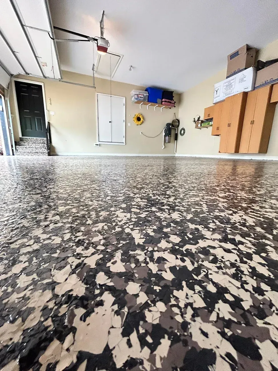 Garage interior with speckled epoxy floor, wall storage, and a garage door opener.