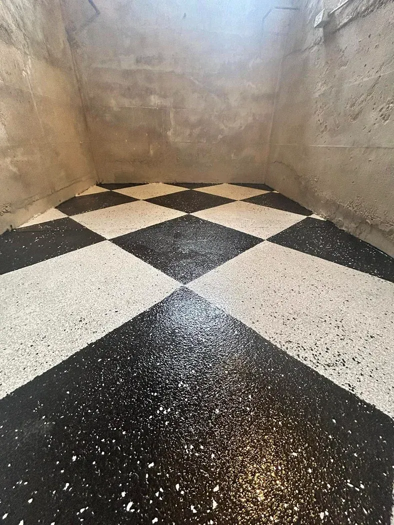 Black-and-white checkerboard floor in a narrow, worn concrete room