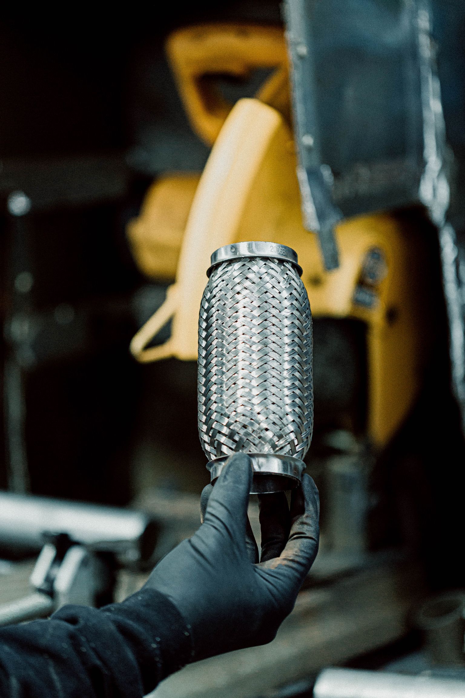 Une personne portant des gants noirs tient un tuyau en métal dans sa main.