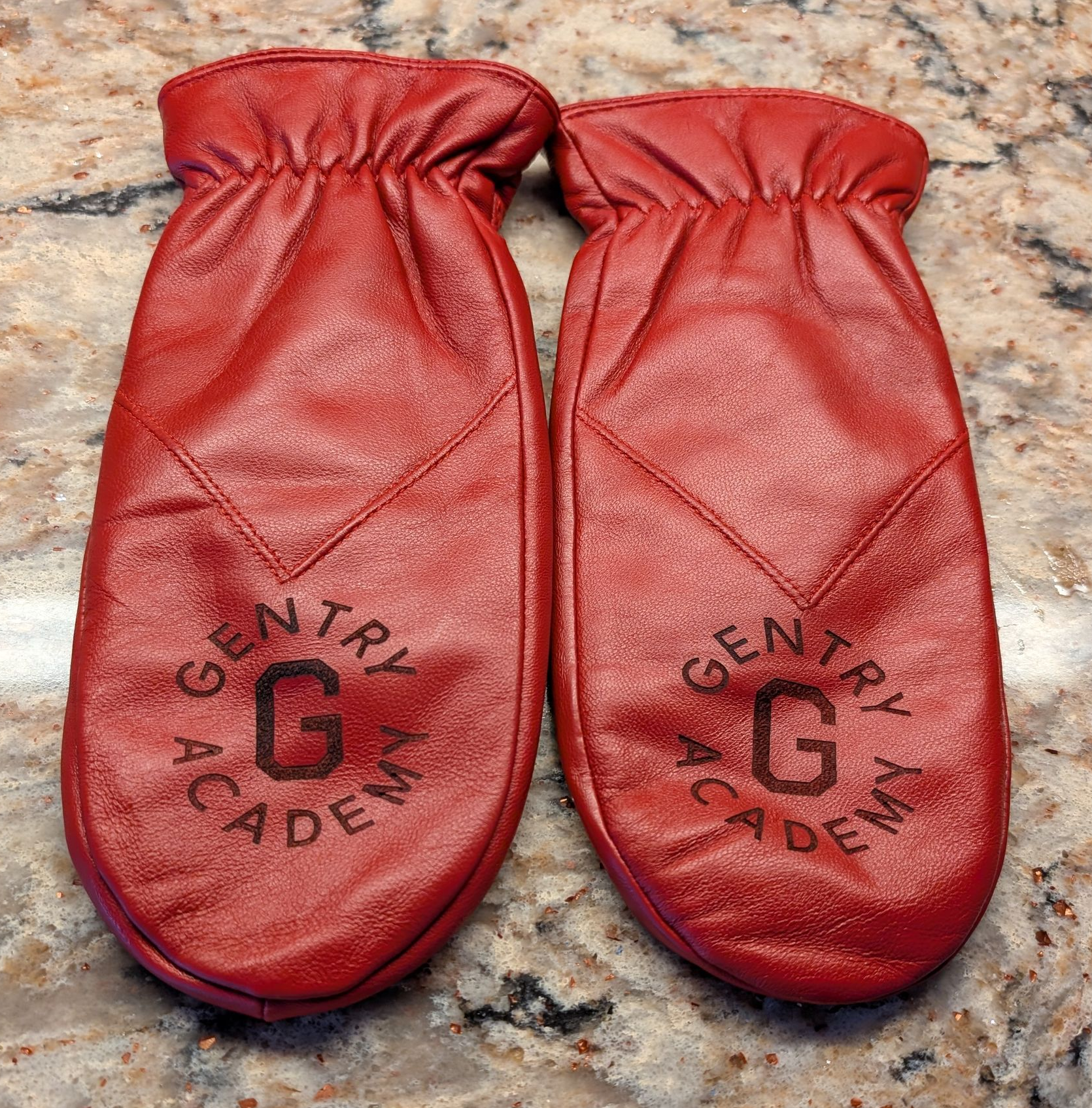 Red leather gloves branded with Gentry Academy logo.