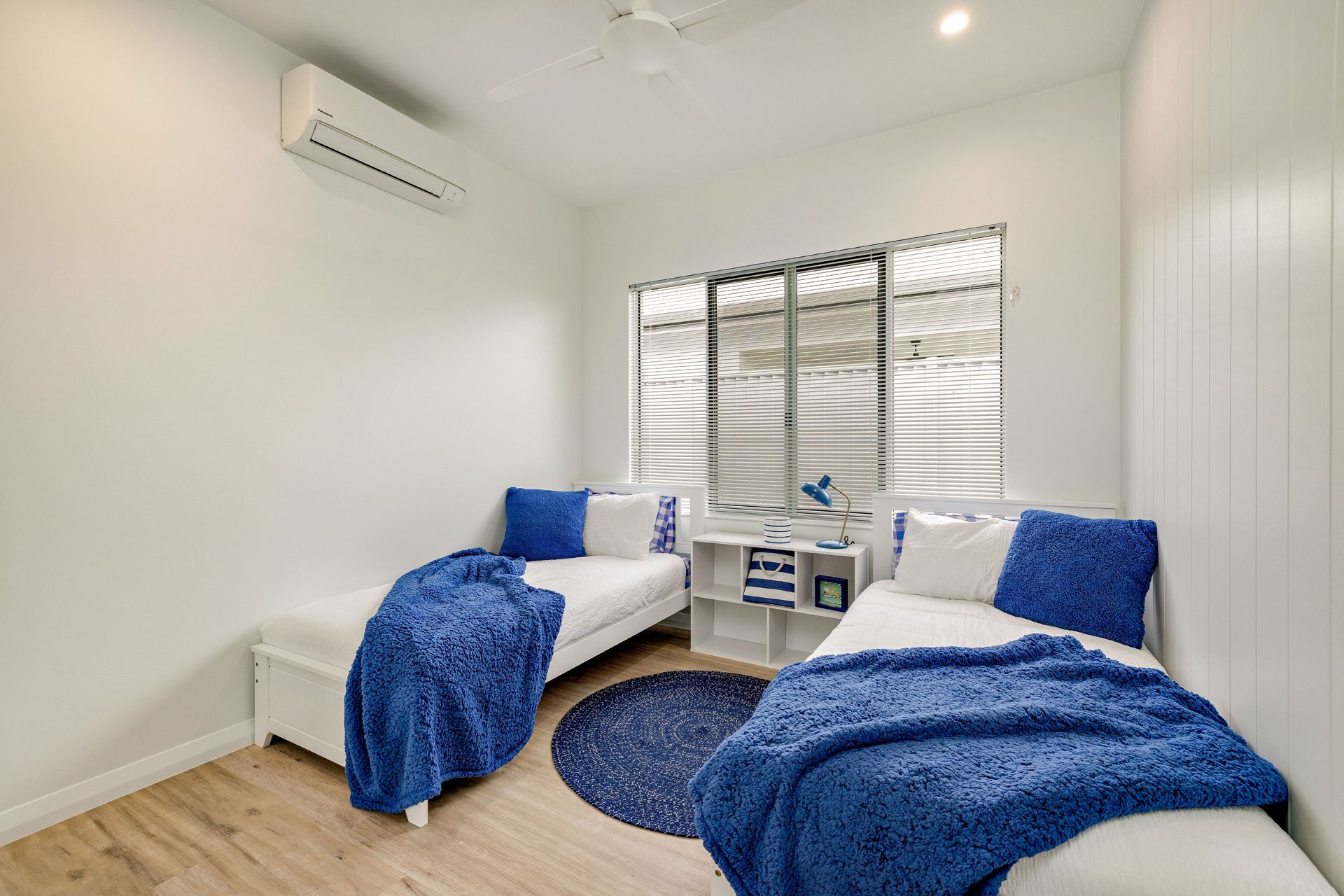 A Bright Bedroom With Two Single Beds Featuring Blue Textured Throws — Ashlee Jones Homes in Gordonvale, QLD