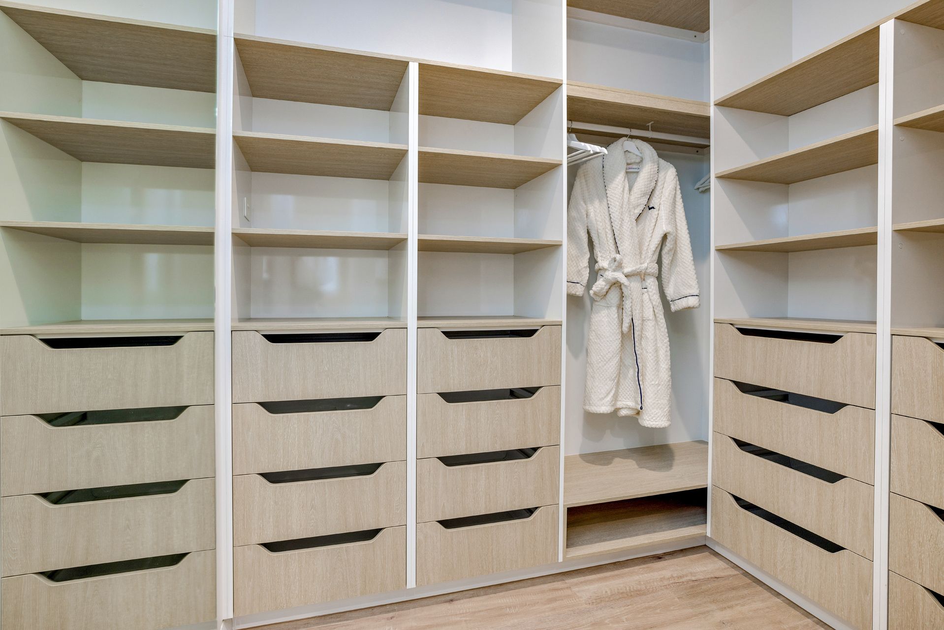 A Walk-in Closet With Light-wood Shelves and Drawers — Ashlee Jones Homes in Gordonvale, QLD