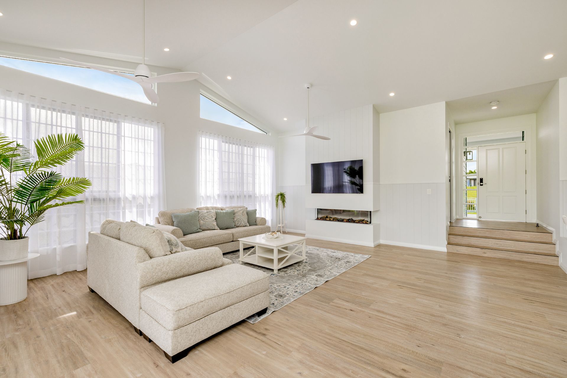 A Bright, Modern Living Room With Light Wood Floors — Ashlee Jones Homes in Gordonvale, QLD