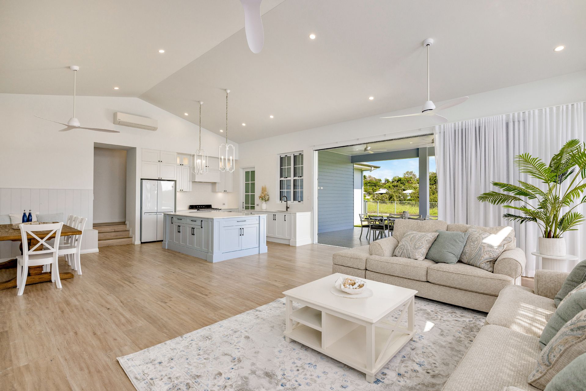 A Spacious, Modern Open-plan Living and Kitchen Area With Light Wood Floors — Ashlee Jones Homes in Gordonvale, QLD