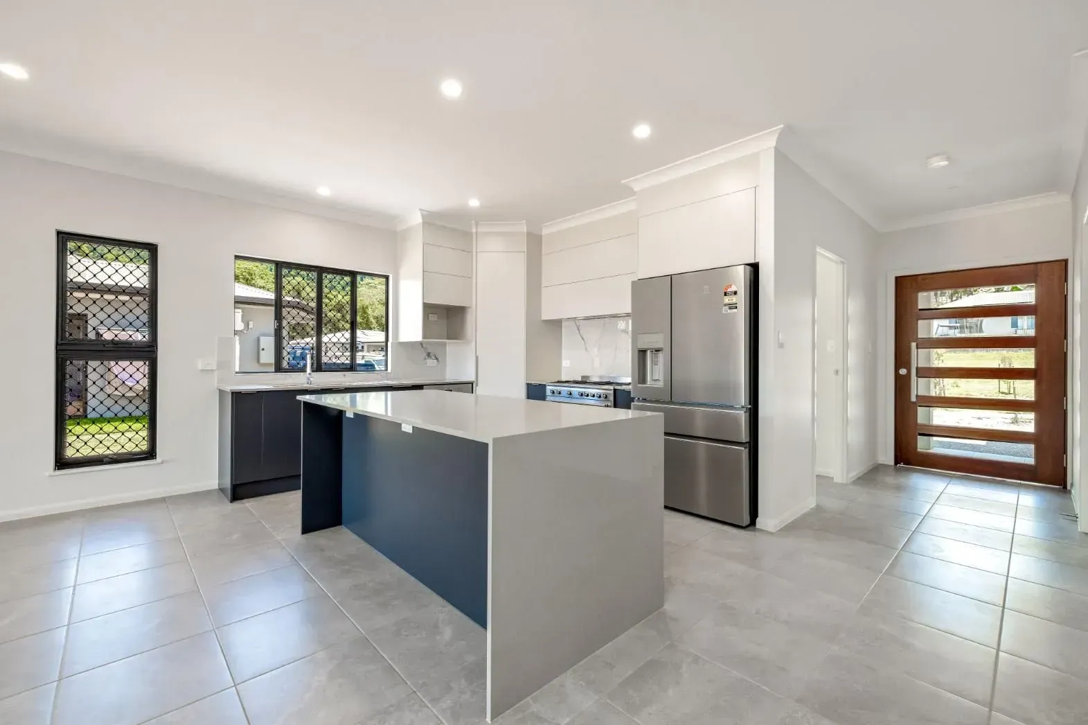 An Empty Living Room With Sliding Glass Doors and a Ceiling Fan — Ashlee Jones Homes in Gordonvale, QLD