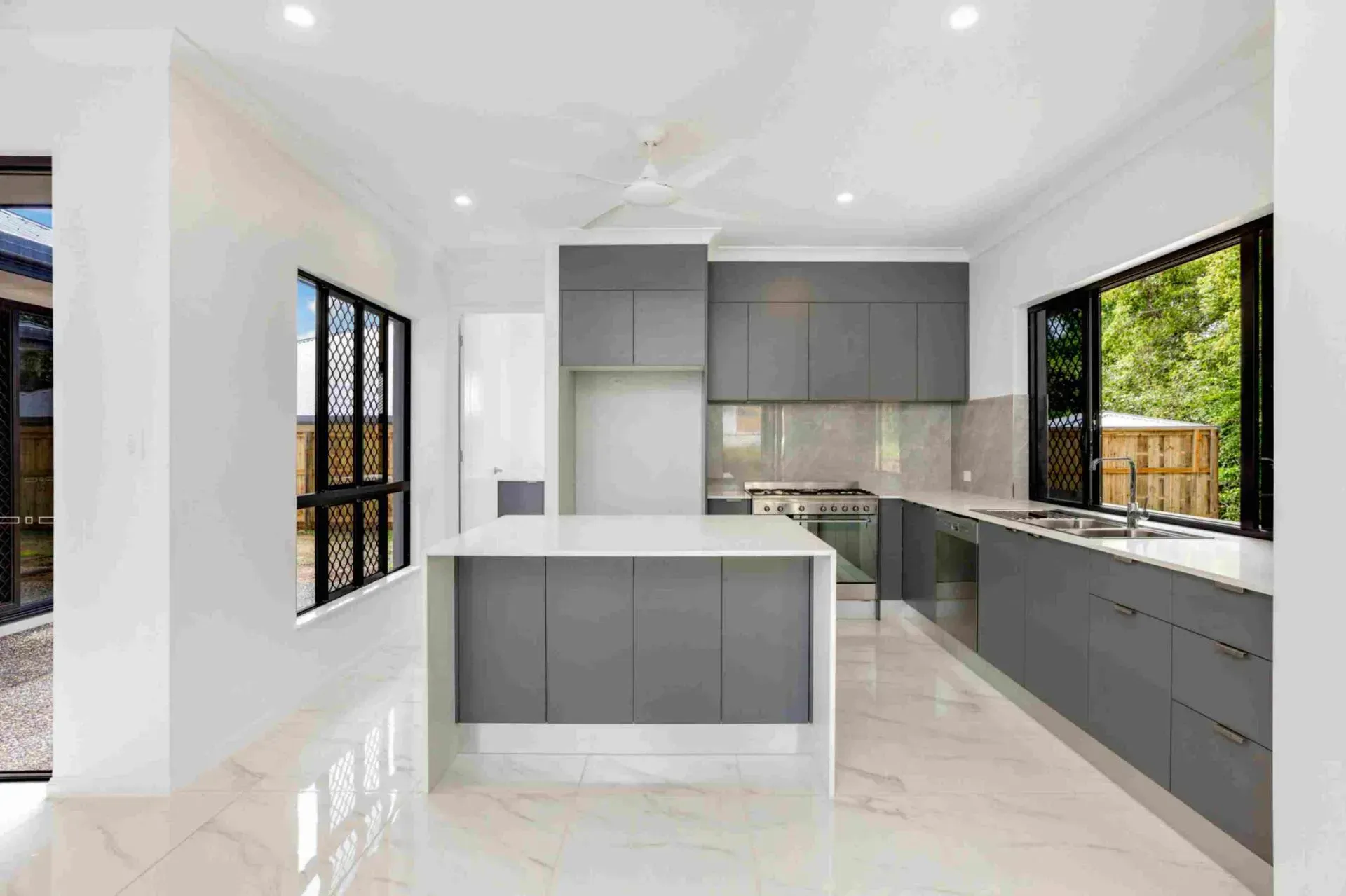An Empty Kitchen With Gray Cabinets And White Counter Tops — Ashlee Jones Homes in Gordonvale, QLD