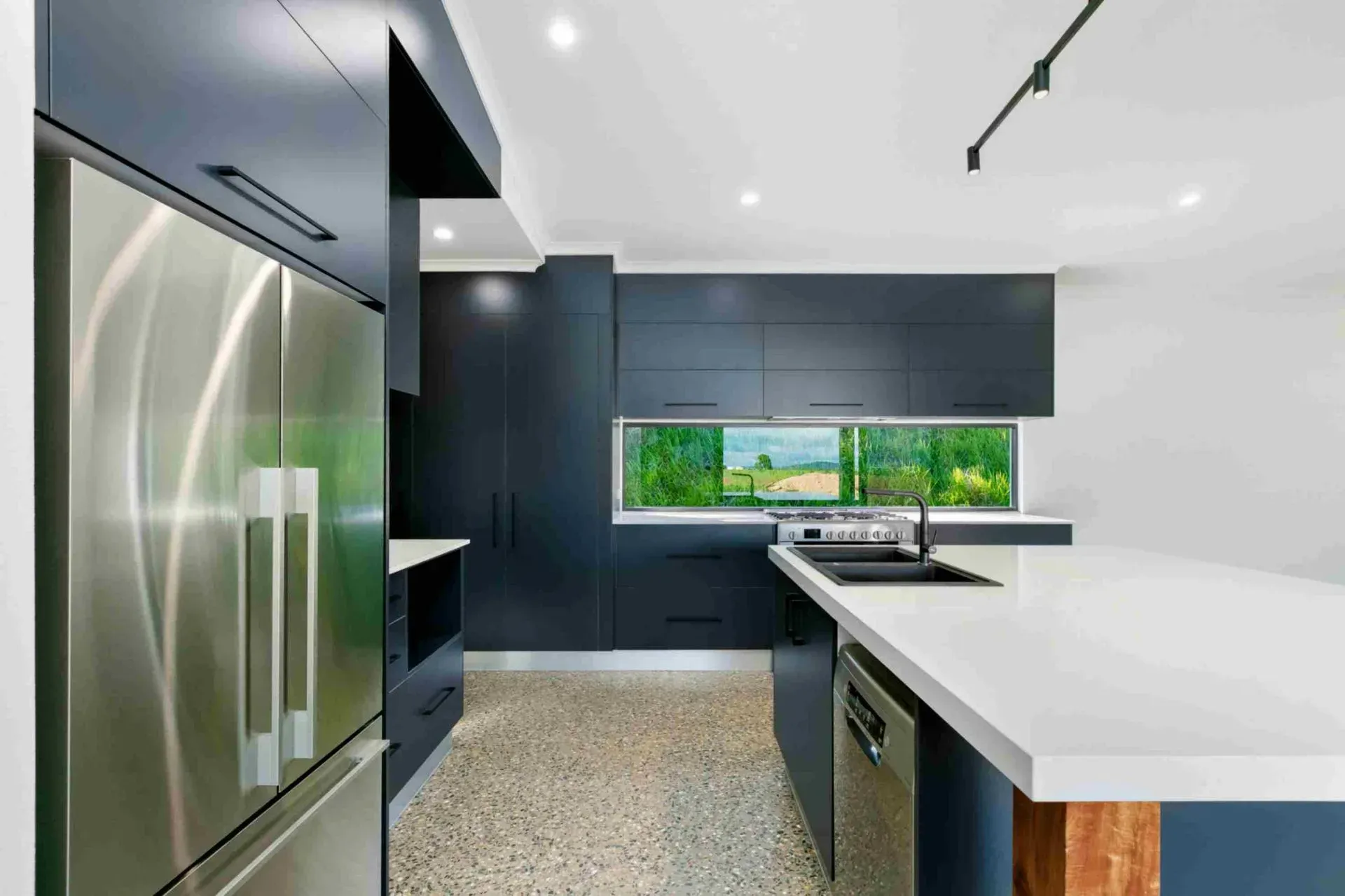 A Kitchen With Stainless Steel Appliances and Blue Cabinets — Ashlee Jones Homes in Tablelands, QLD