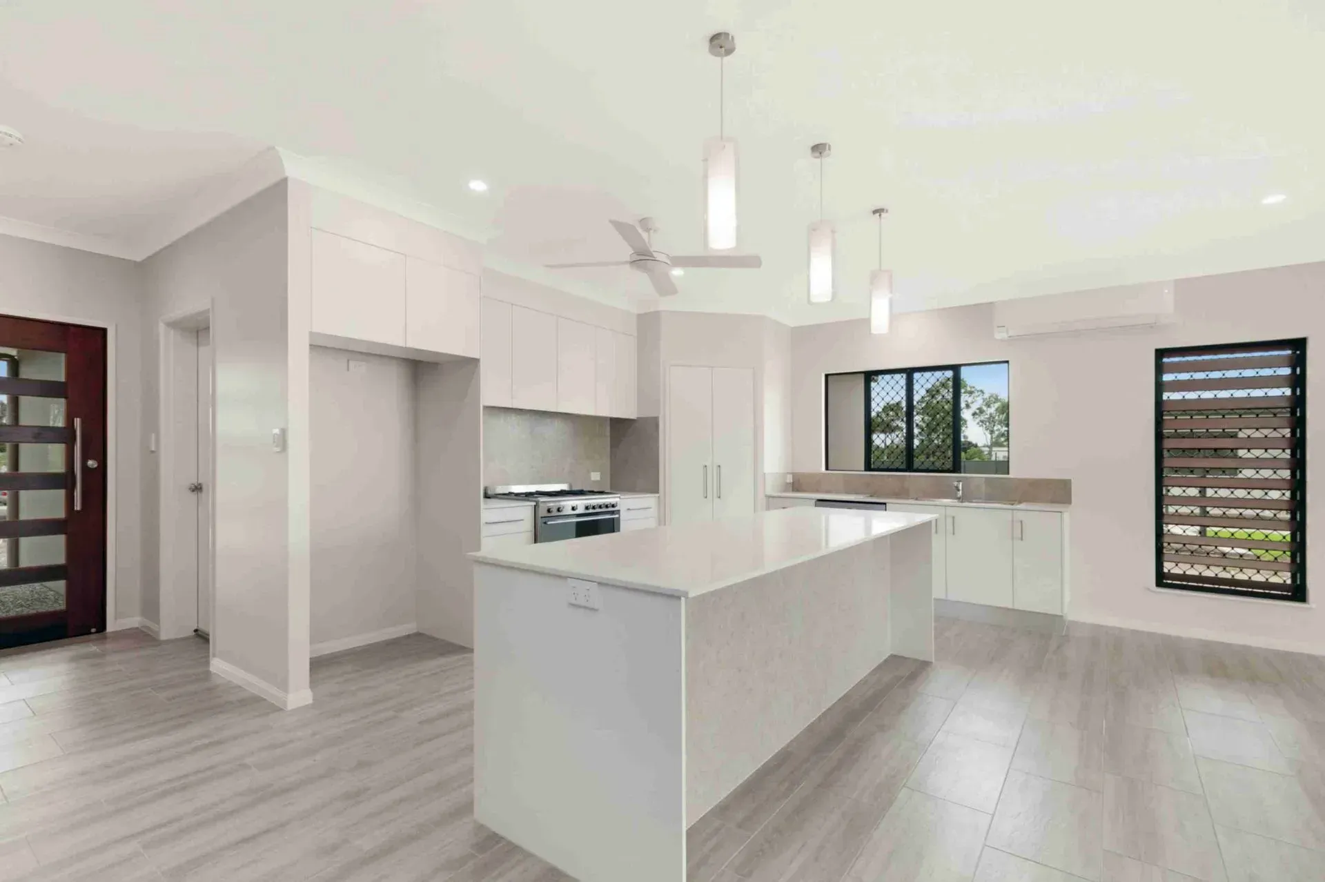 A Kitchen With White Cabinets and a Large Island in the Middle of the Room — Ashlee Jones Homes in Gordonvale, QLD
