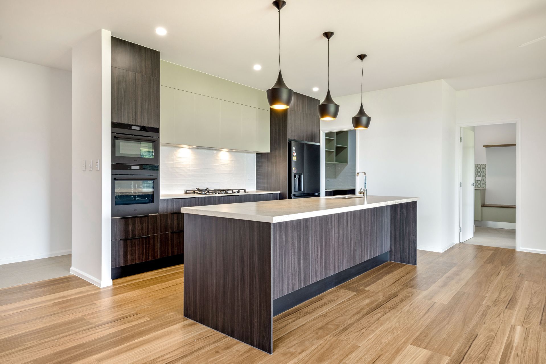 A Modern Kitchen With a Large Dark Wood Island — Ashlee Jones Homes in Gordonvale, QLD