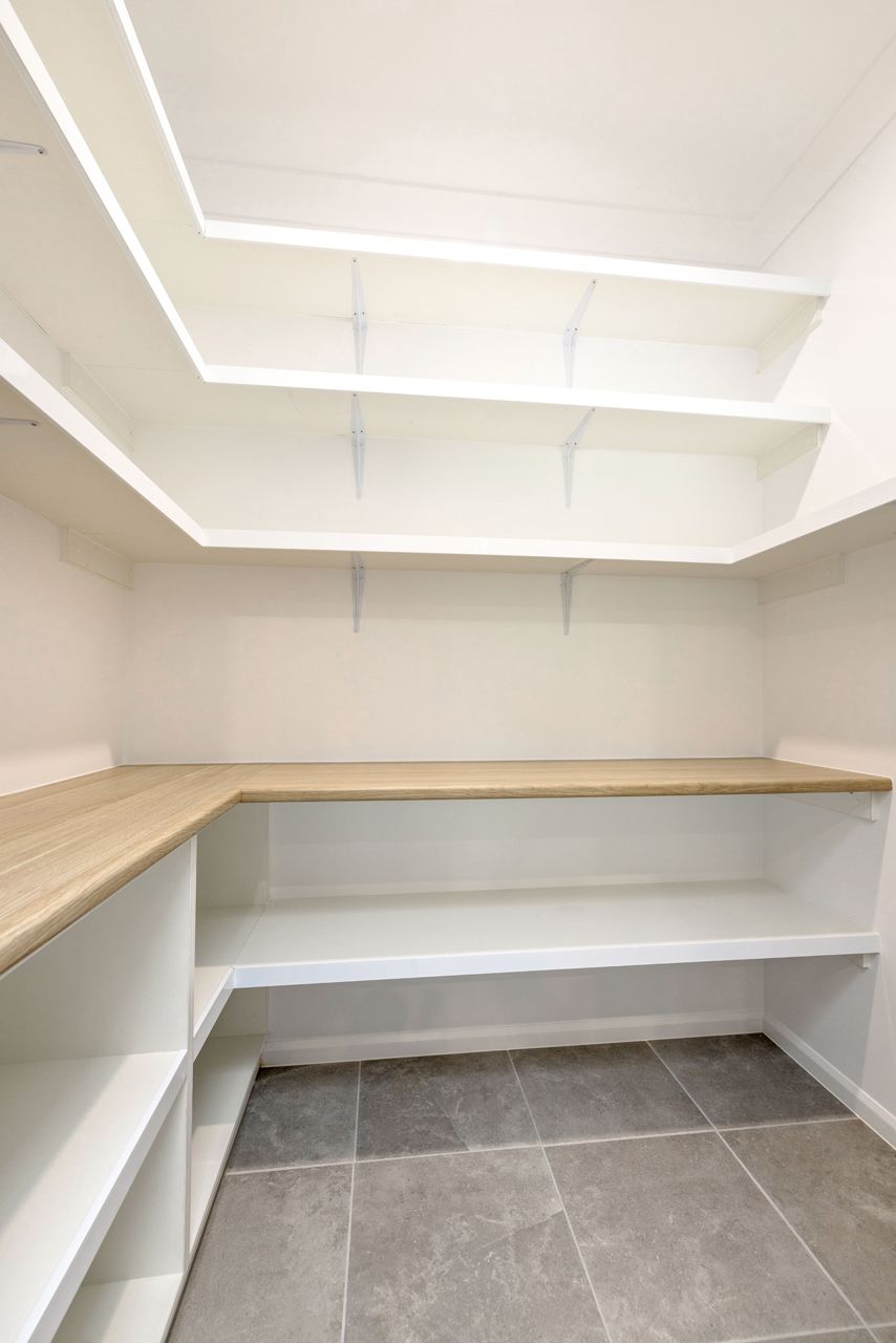 A Walk-in Pantry With White Shelves, a Light Wood-tone Countertop — Ashlee Jones Homes in Gordonvale, QLD