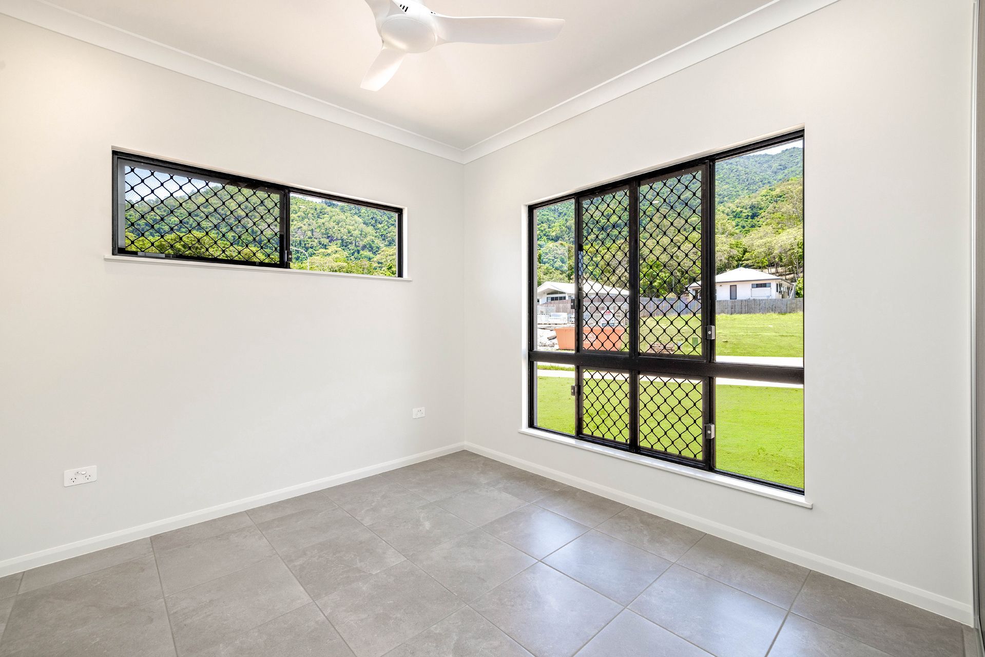 A Brightly Lit, Empty Room With Grey Tiled Flooring — Ashlee Jones Homes in Gordonvale, QLD