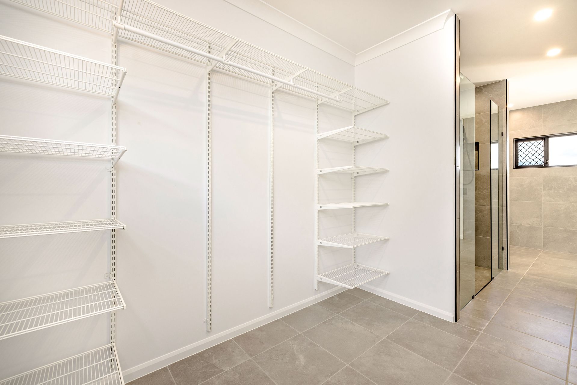 A Walk-in Closet Featuring White Wire Shelving on White Walls — Ashlee Jones Homes in Gordonvale, QLD