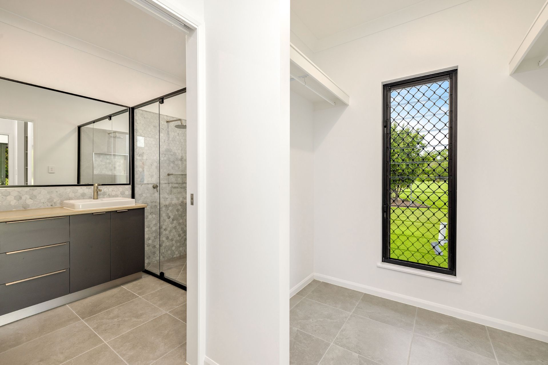 A Modern Ensuite Bathroom With a Dark Vanity and Walk-in Shower — Ashlee Jones Homes in Gordonvale, QLD