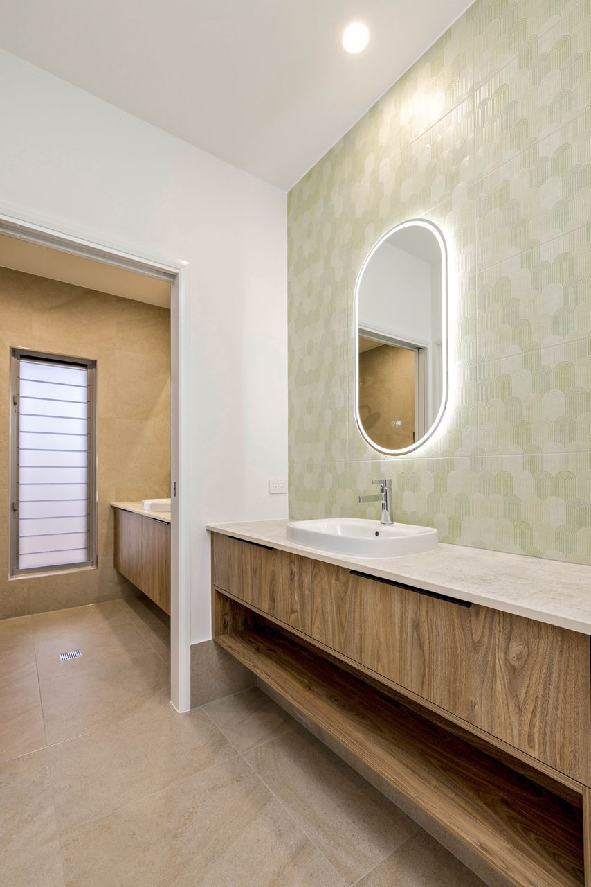 A Modern Bathroom With a Light Wood Floating Vanity — Ashlee Jones Homes in Gordonvale, QLD