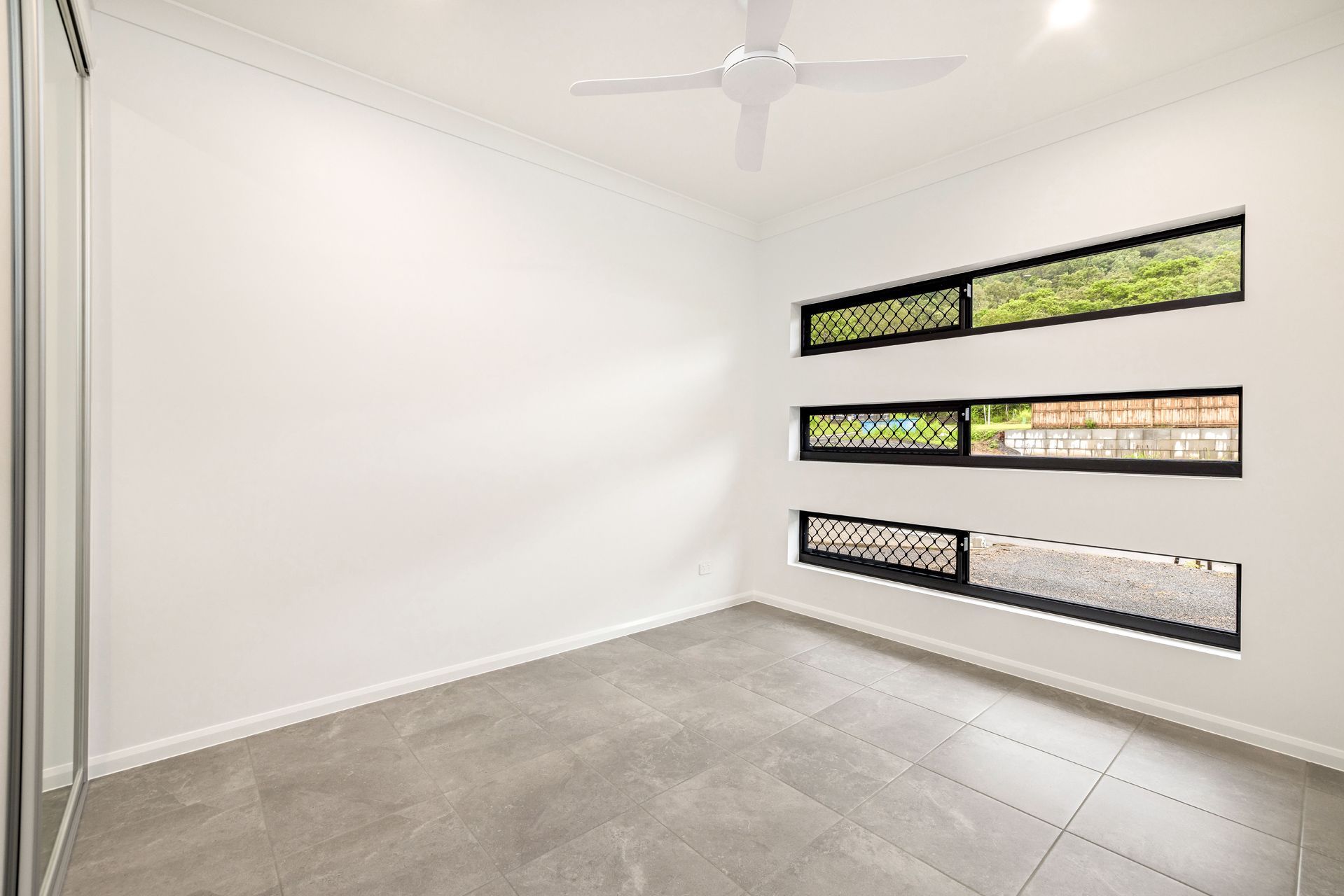 An Empty Room With White Walls, Gray Tiled Floors — Ashlee Jones Homes in Gordonvale, QLD