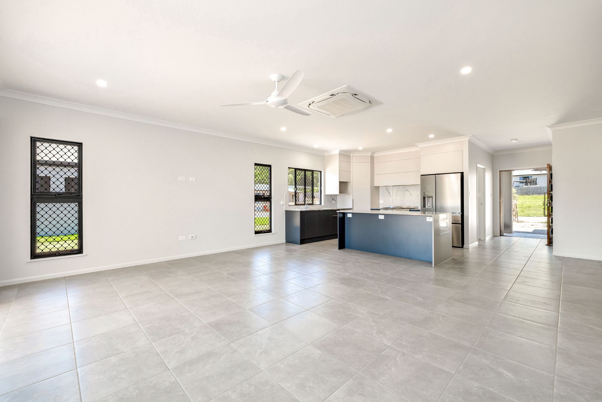 An Open-concept Living and Kitchen Area With Light Grey Tiled Floors — Ashlee Jones Homes in Gordonvale, QLD