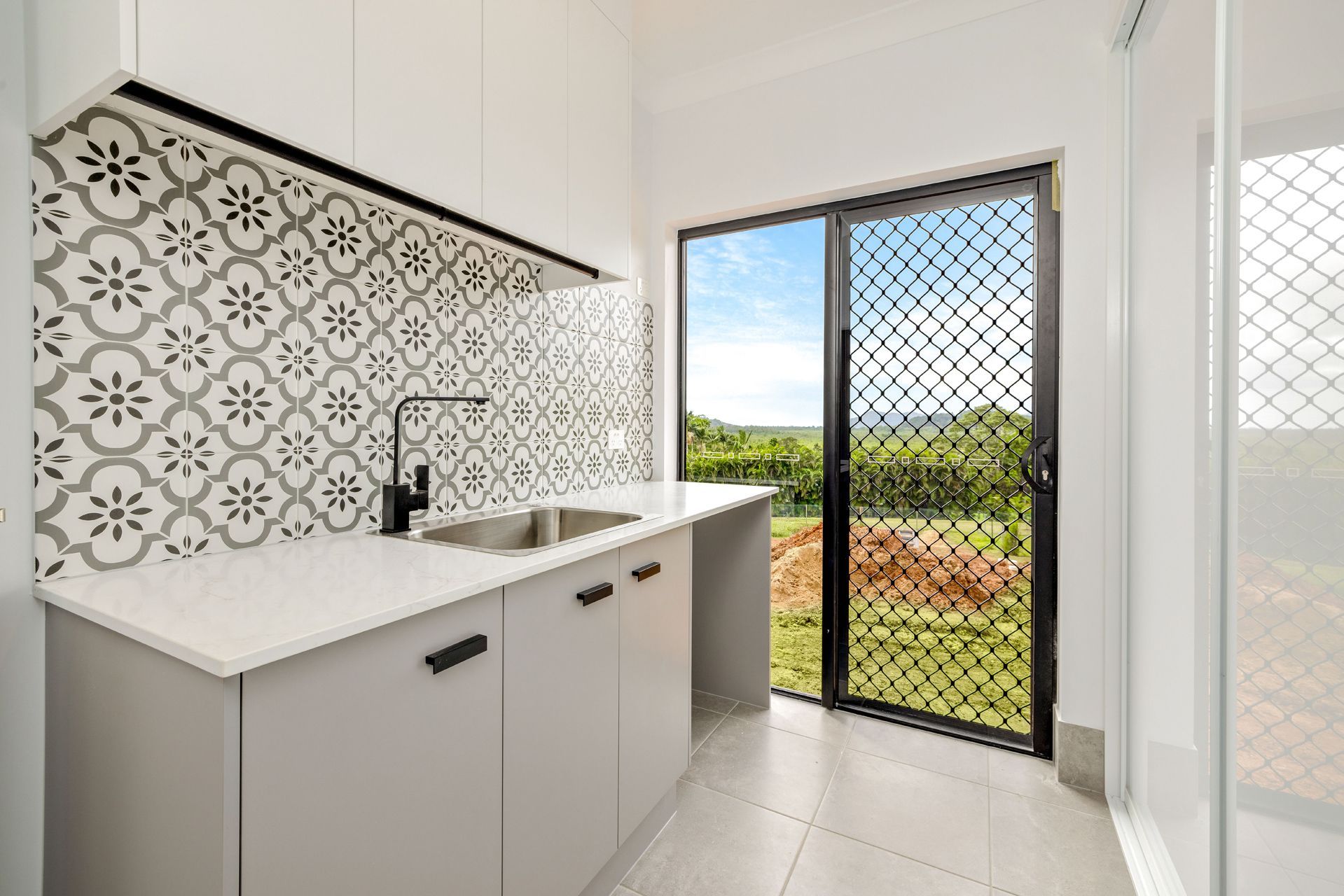 A Small Modern Laundry or Kitchenette With White Cabinets — Ashlee Jones Homes in Gordonvale, QLD