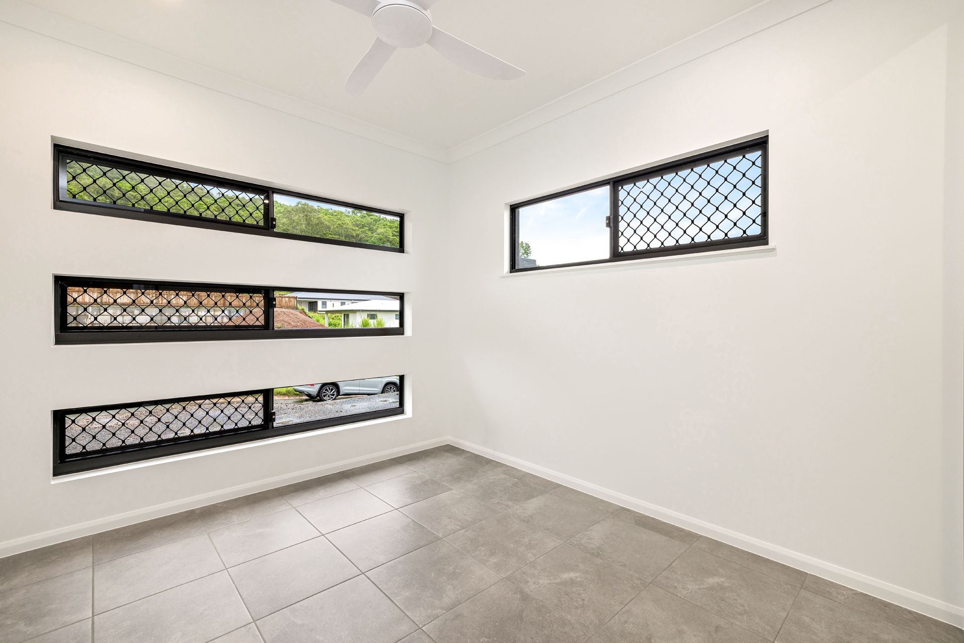 A Bright, Empty Room With Grey Tiled Floors — Ashlee Jones Homes in Gordonvale, QLD