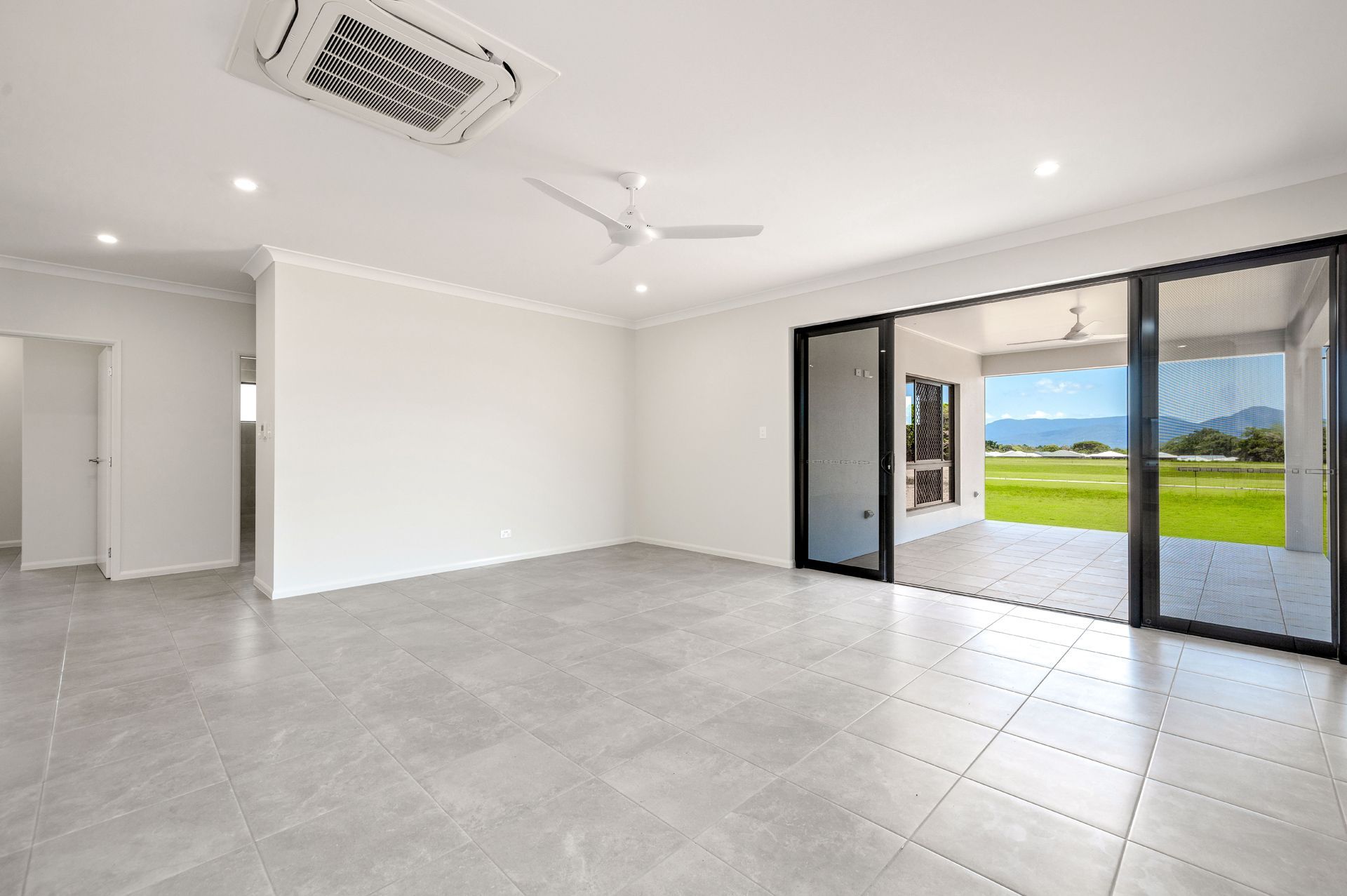 A Bright, Modern Empty Room With Large Grey Floor Tiles — Ashlee Jones Homes in Gordonvale, QLD