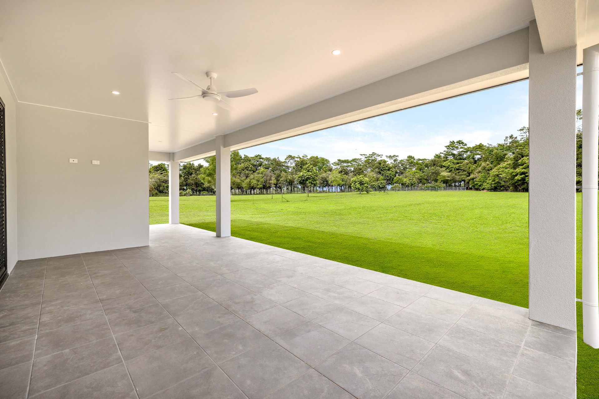 A Modern Covered Patio With Grey Tiled Flooring — Ashlee Jones Homes in Gordonvale, QLD