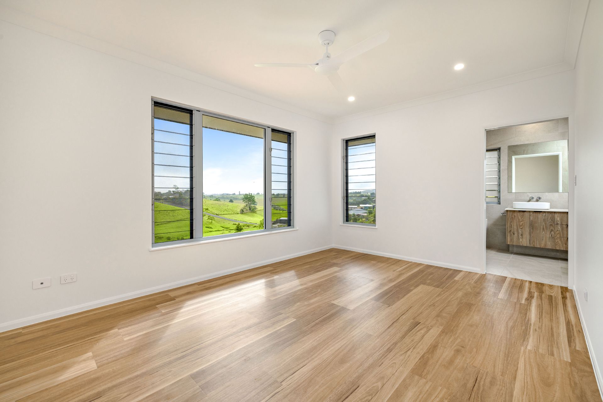 A Bright, Empty Bedroom With Light Wood Flooring, White Walls — Ashlee Jones Homes in Gordonvale, QLD