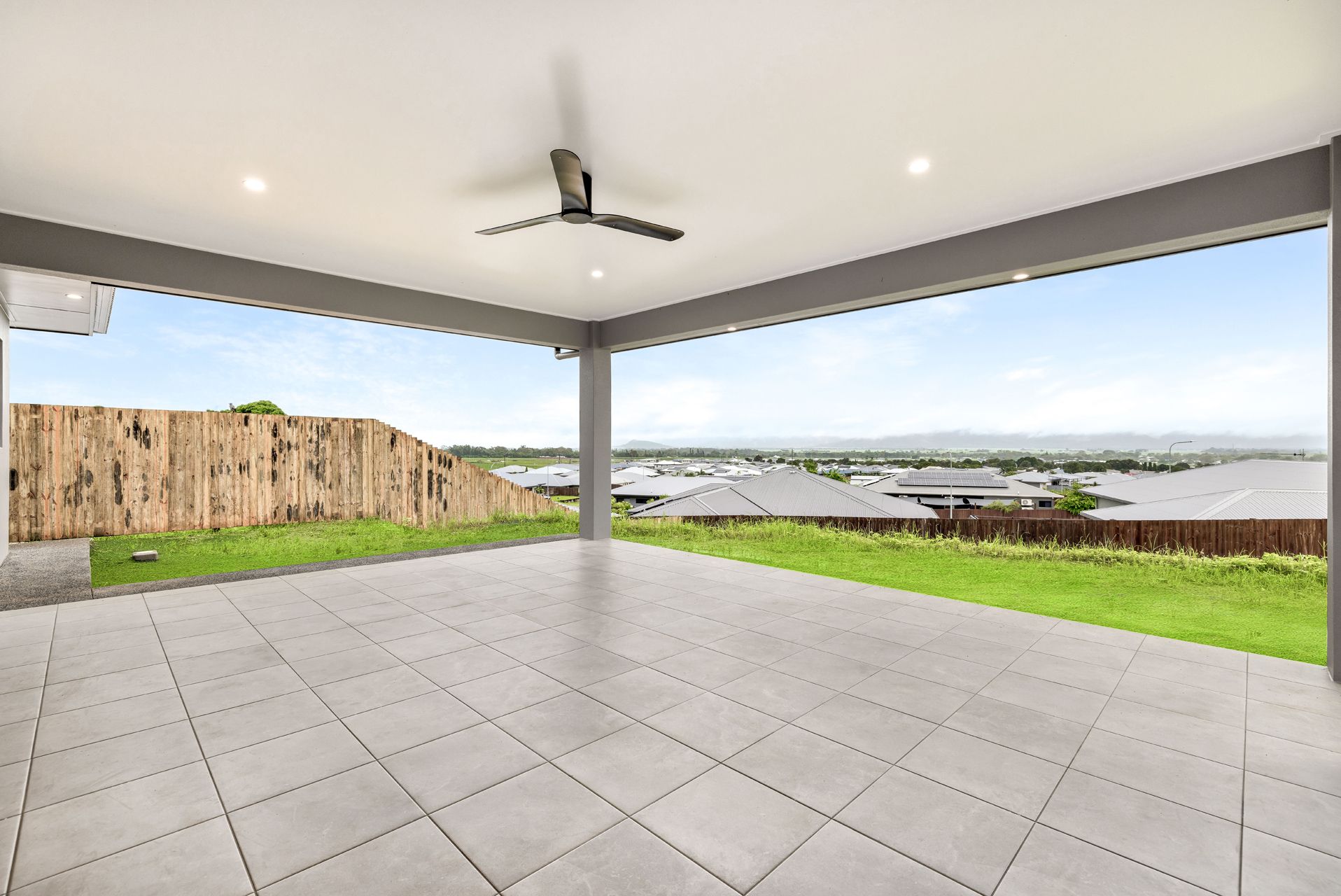 A Spacious, Tiled Outdoor Patio Under a Covered Roof With a Ceiling Fan — Ashlee Jones Homes in Gordonvale, QLD