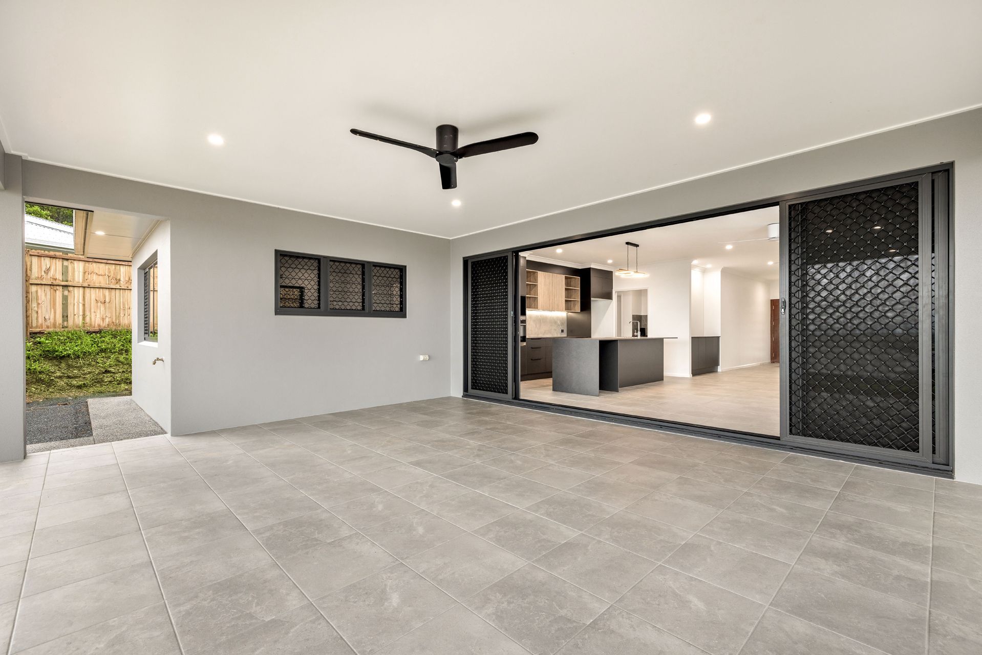 A Spacious Covered Patio With Grey Stone Tiles and a Ceiling Fan — Ashlee Jones Homes in Gordonvale, QLD