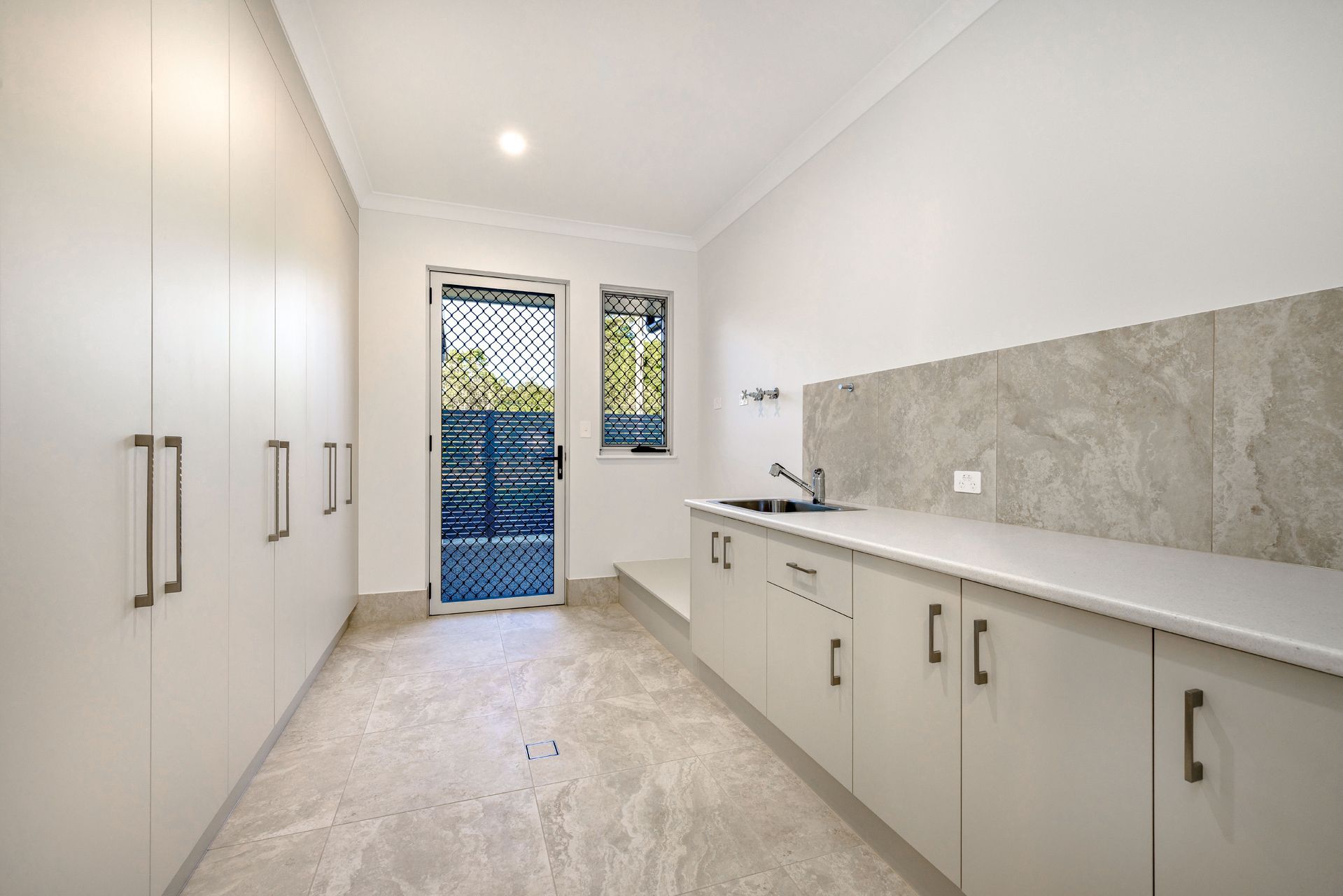 A Bright Laundry Room With White Floor-to-ceiling Cabinets — Ashlee Jones Homes in Gordonvale, QLD
