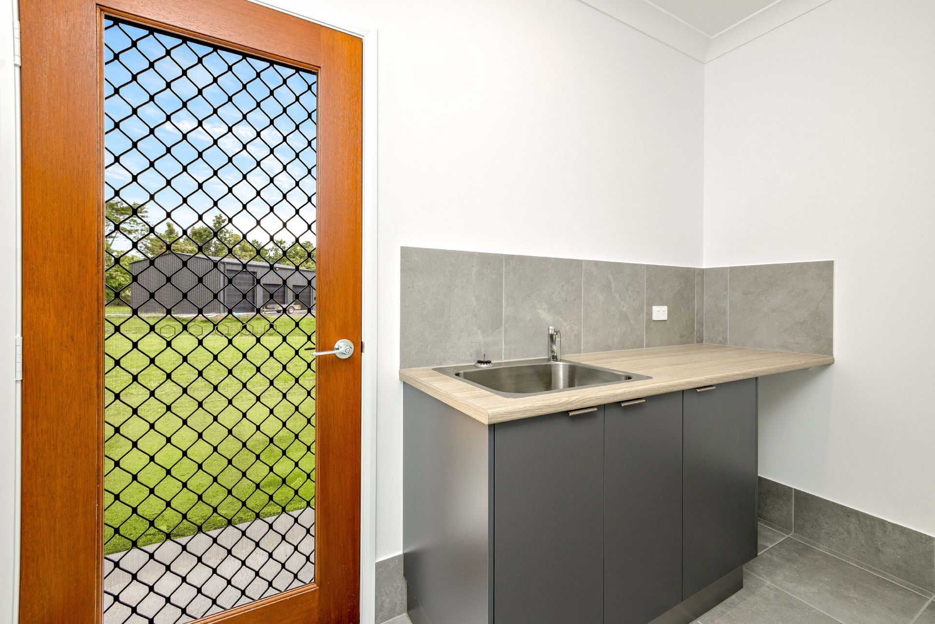 A Laundry Room With a Gray Cabinet and Sink — Ashlee Jones Homes in Gordonvale, QLD