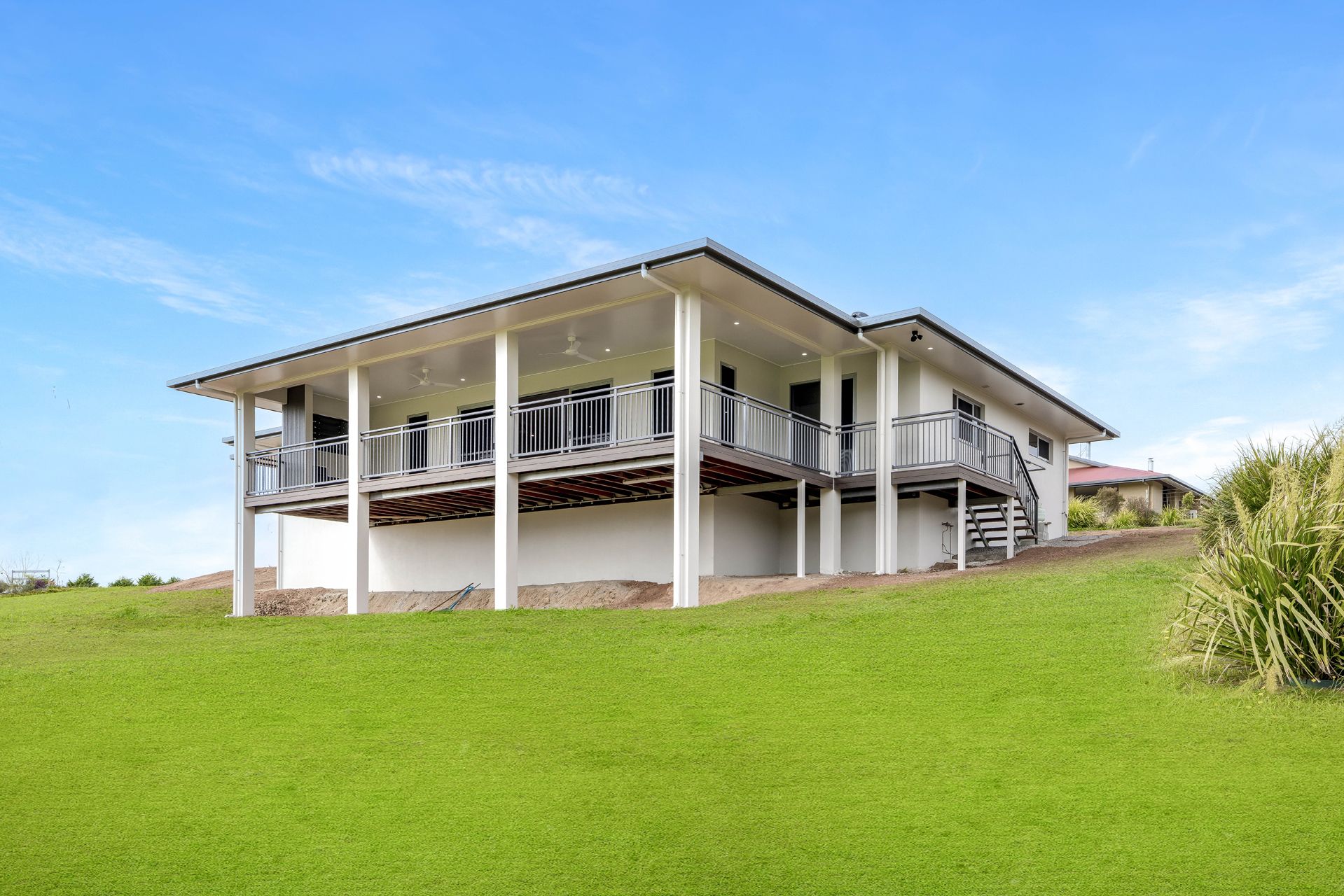 A White, Single-story House With a Large Wrap-around Deck on Stilts — Ashlee Jones Homes in Gordonvale, QLD