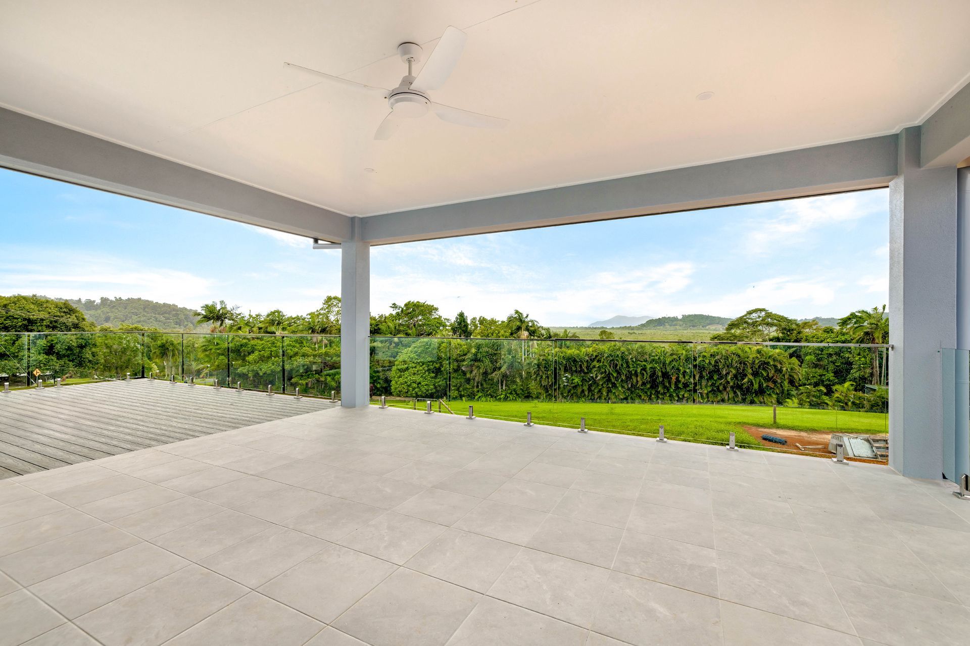 A Spacious, Covered Outdoor Patio With Light Gray Tiled Flooring — Ashlee Jones Homes in Gordonvale, QLD