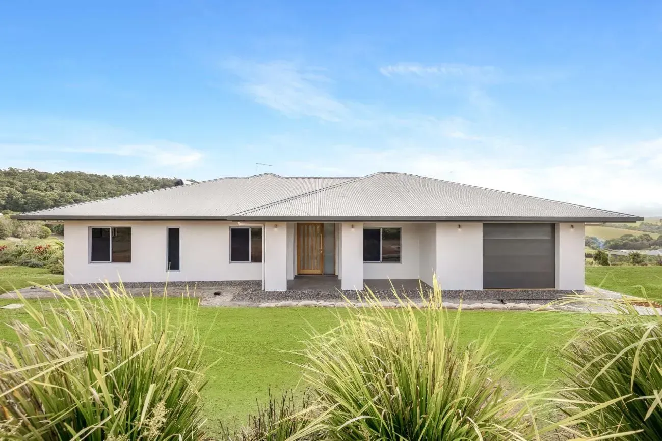 A Large White House is Sitting on Top of a Lush Green Hill — Ashlee Jones Homes in Gordonvale, QLD