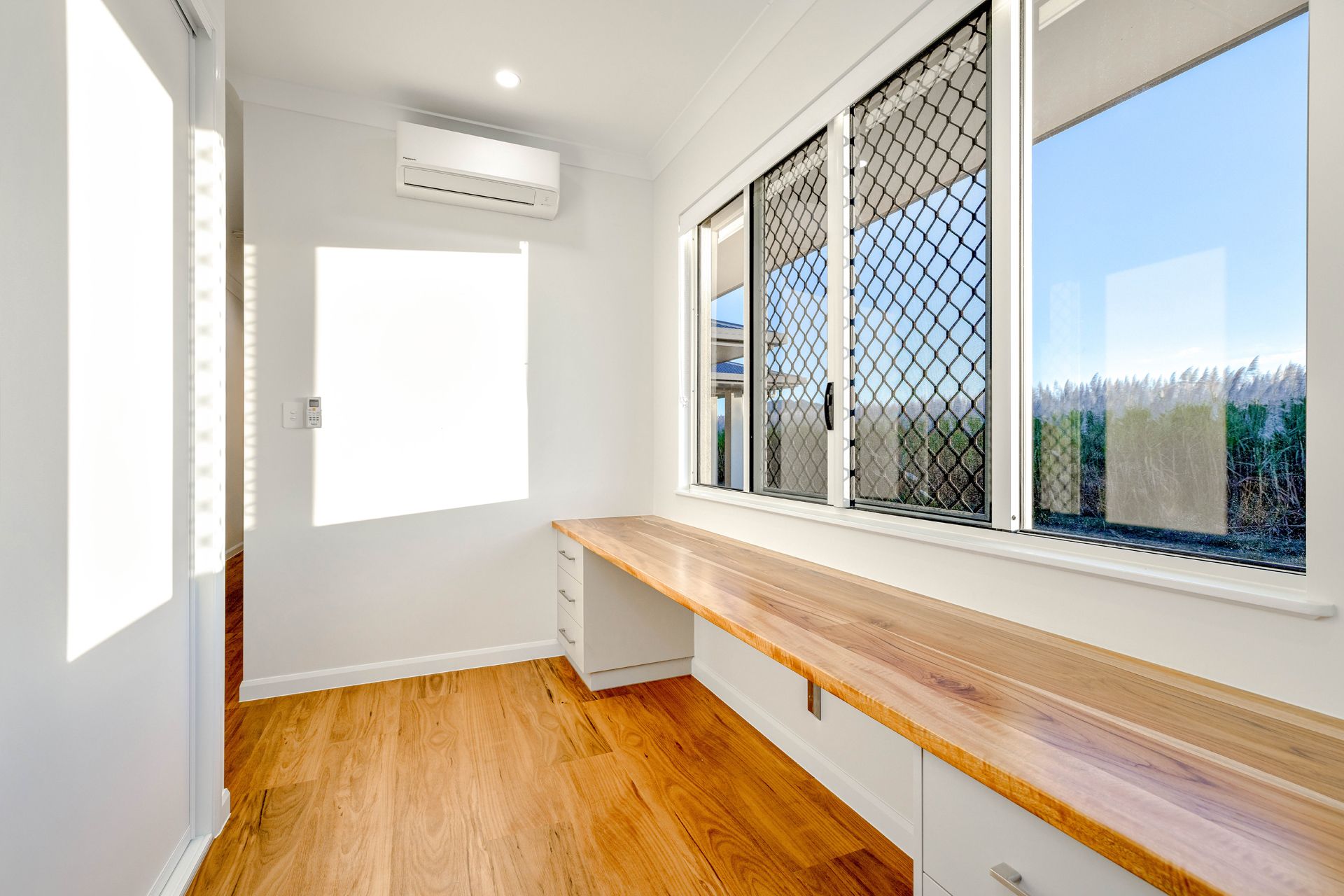 A Bright, Modern Home Office With Wooden Flooring — Ashlee Jones Homes in Gordonvale, QLD