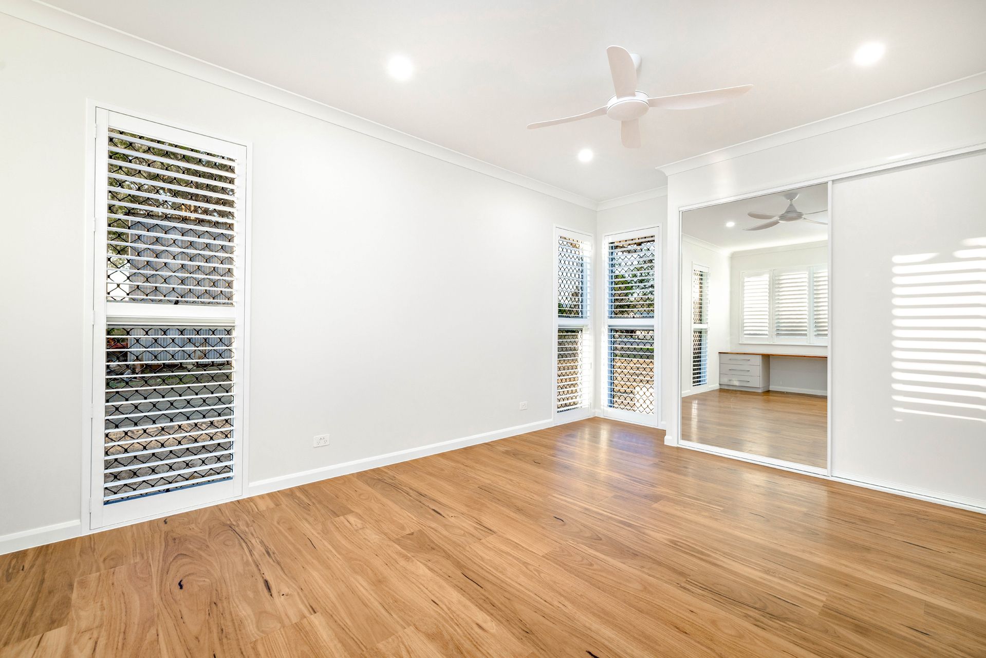 A Bright, Empty Room With Light Wood Floors, White Walls — Ashlee Jones Homes in Gordonvale, QLD