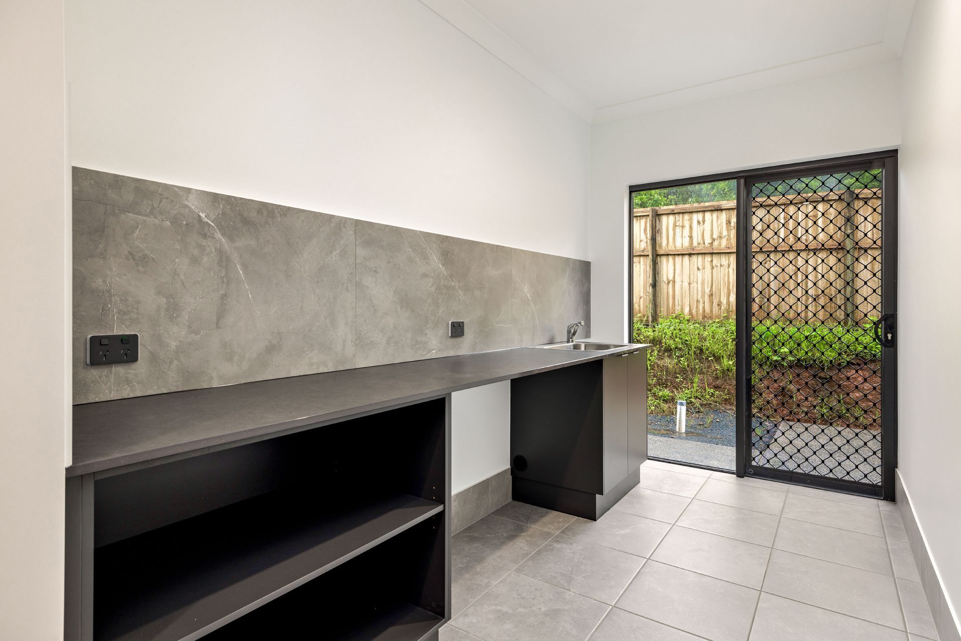 A Laundry Room With Dark Cabinets, a Gray Stone Backsplash — Ashlee Jones Homes in Gordonvale, QLD