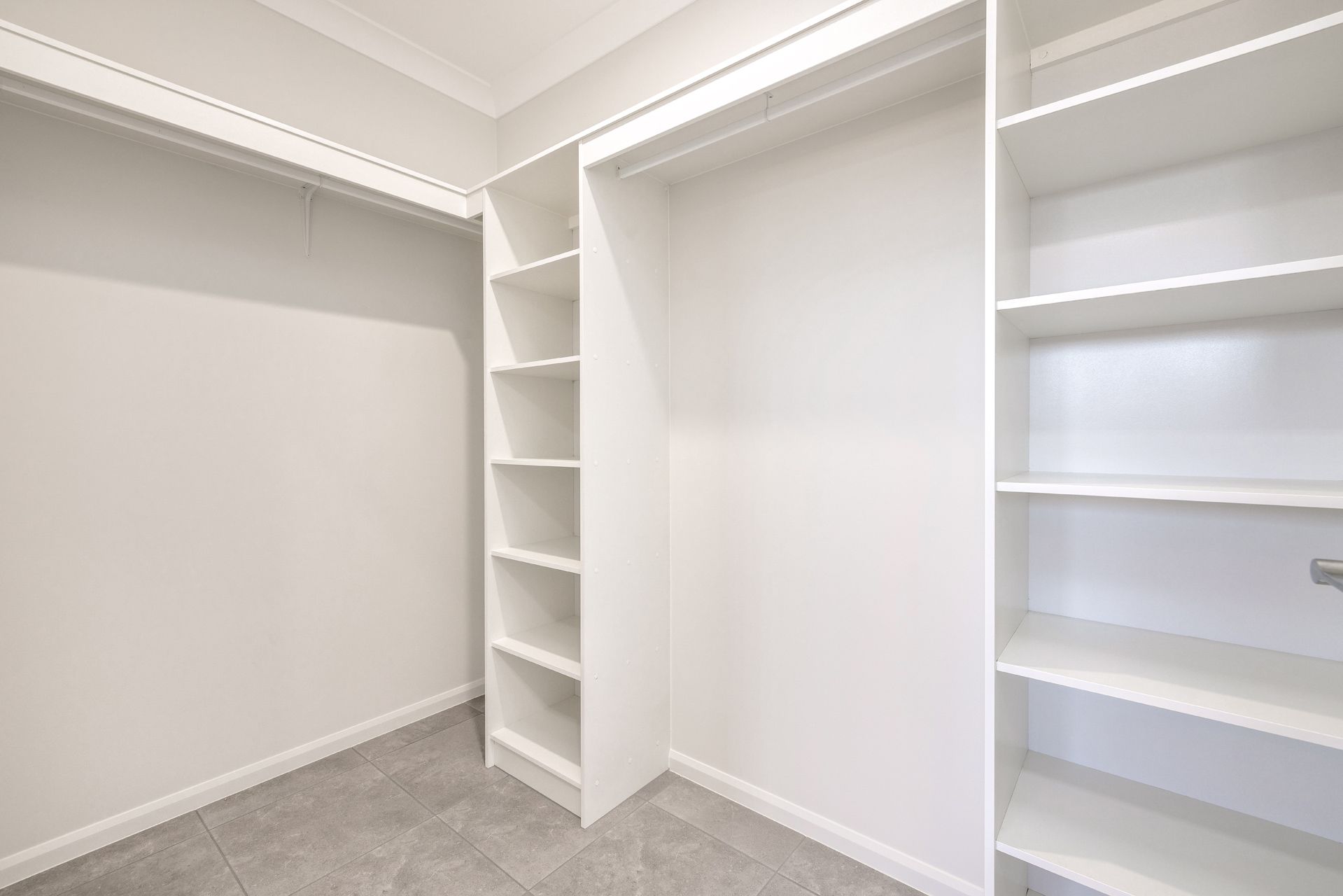A Walk-in Closet Featuring White Wooden Shelving Units — Ashlee Jones Homes in Gordonvale, QLD