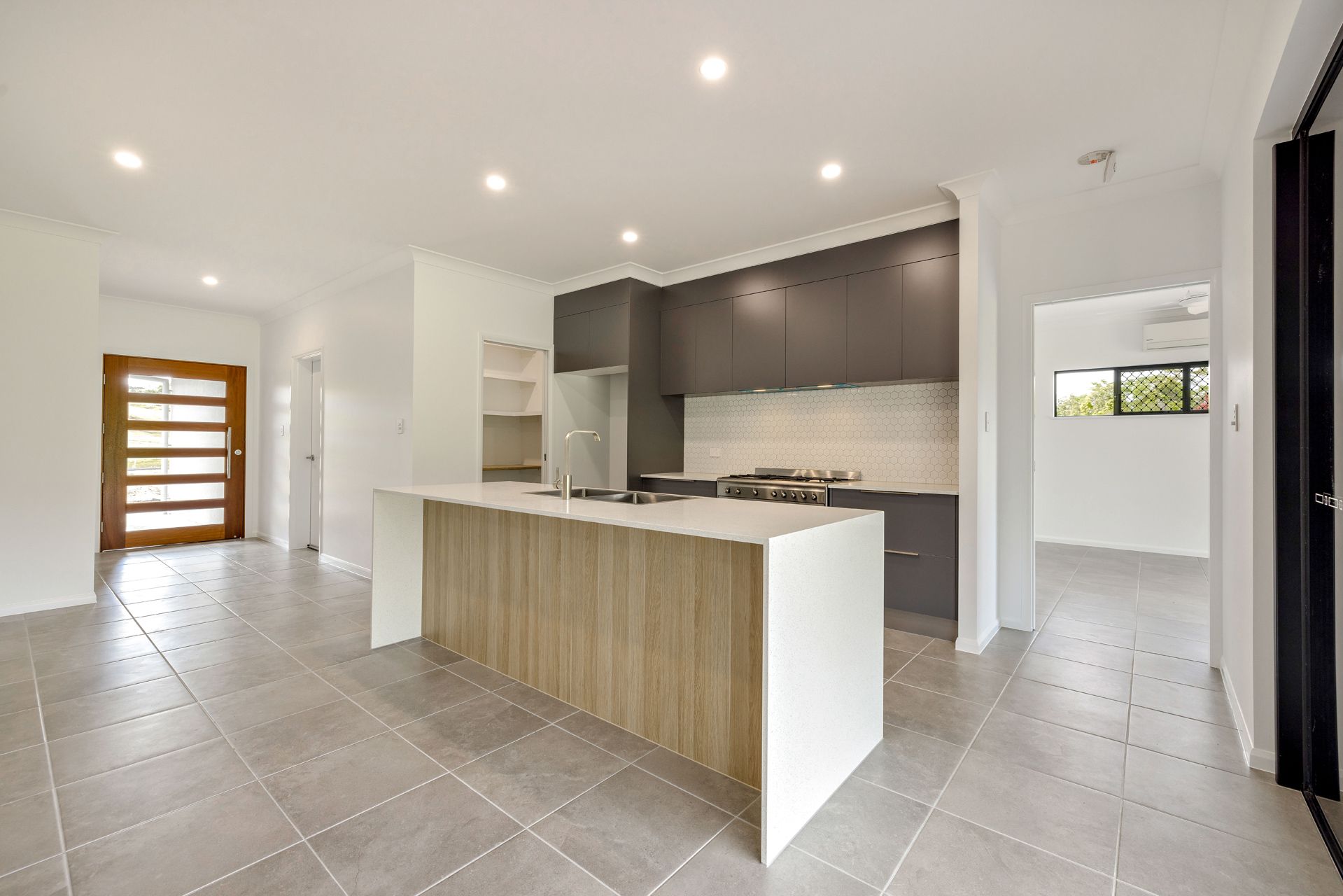 A Modern Kitchen With White Walls, a Wood-paneled Island — Ashlee Jones Homes in Gordonvale, QLD