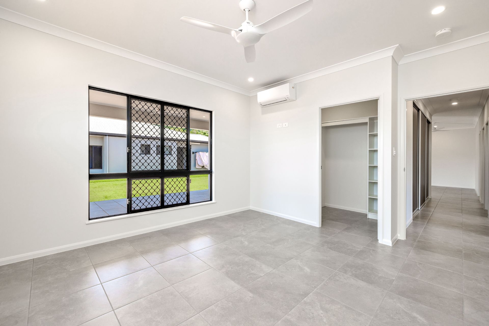 A Bright, Empty Bedroom With Grey Tiled Floors — Ashlee Jones Homes in Gordonvale, QLD