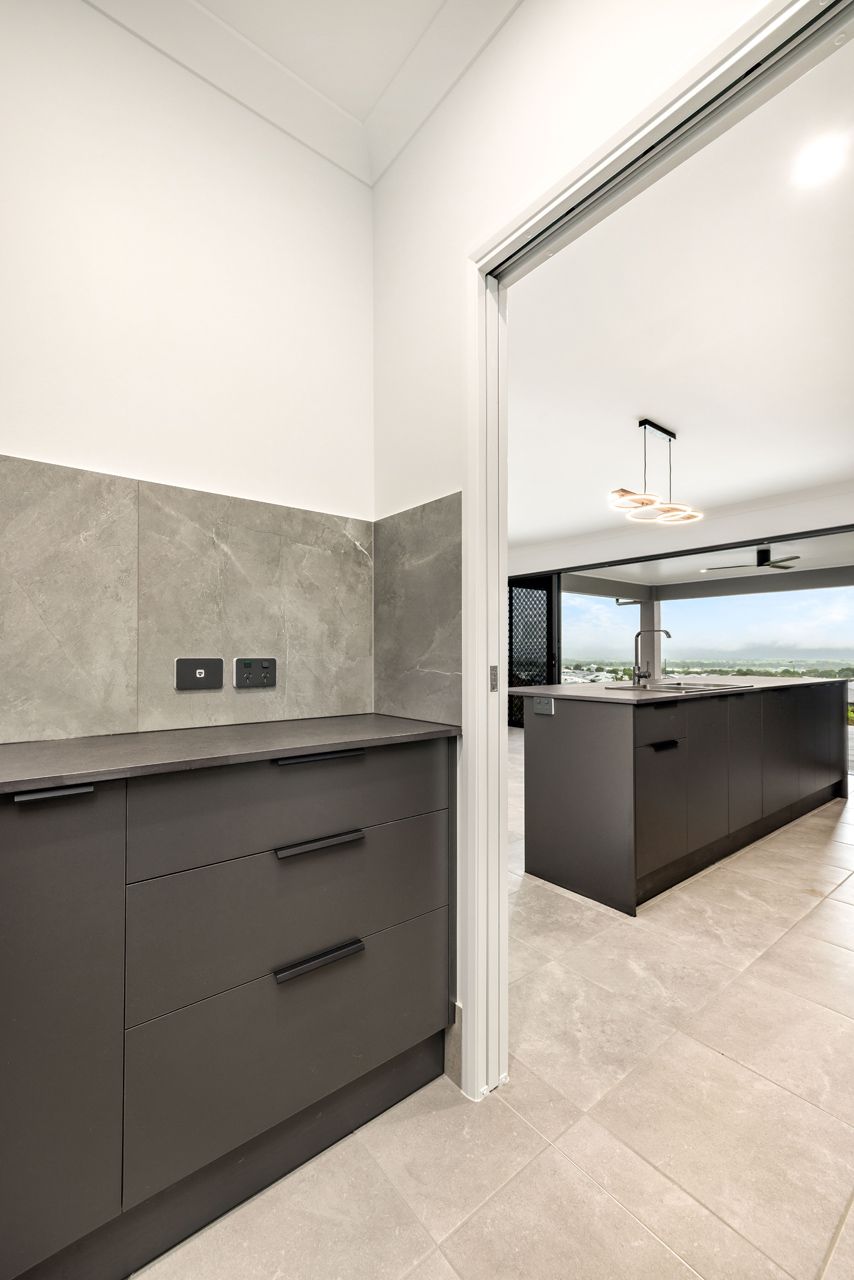 A View From a Utility Space Into a Modern Kitchen — Ashlee Jones Homes in Gordonvale, QLD