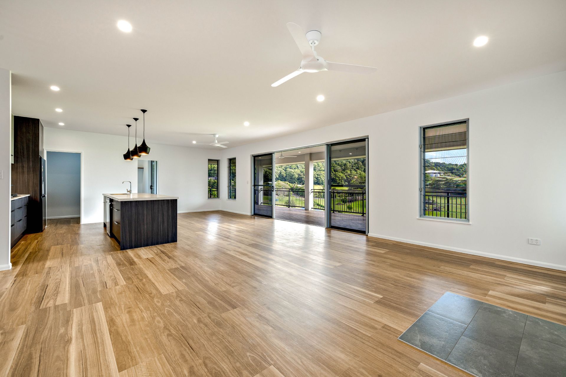 A Modern, Open-concept Living Area With Light Wood Flooring — Ashlee Jones Homes in Gordonvale, QLD