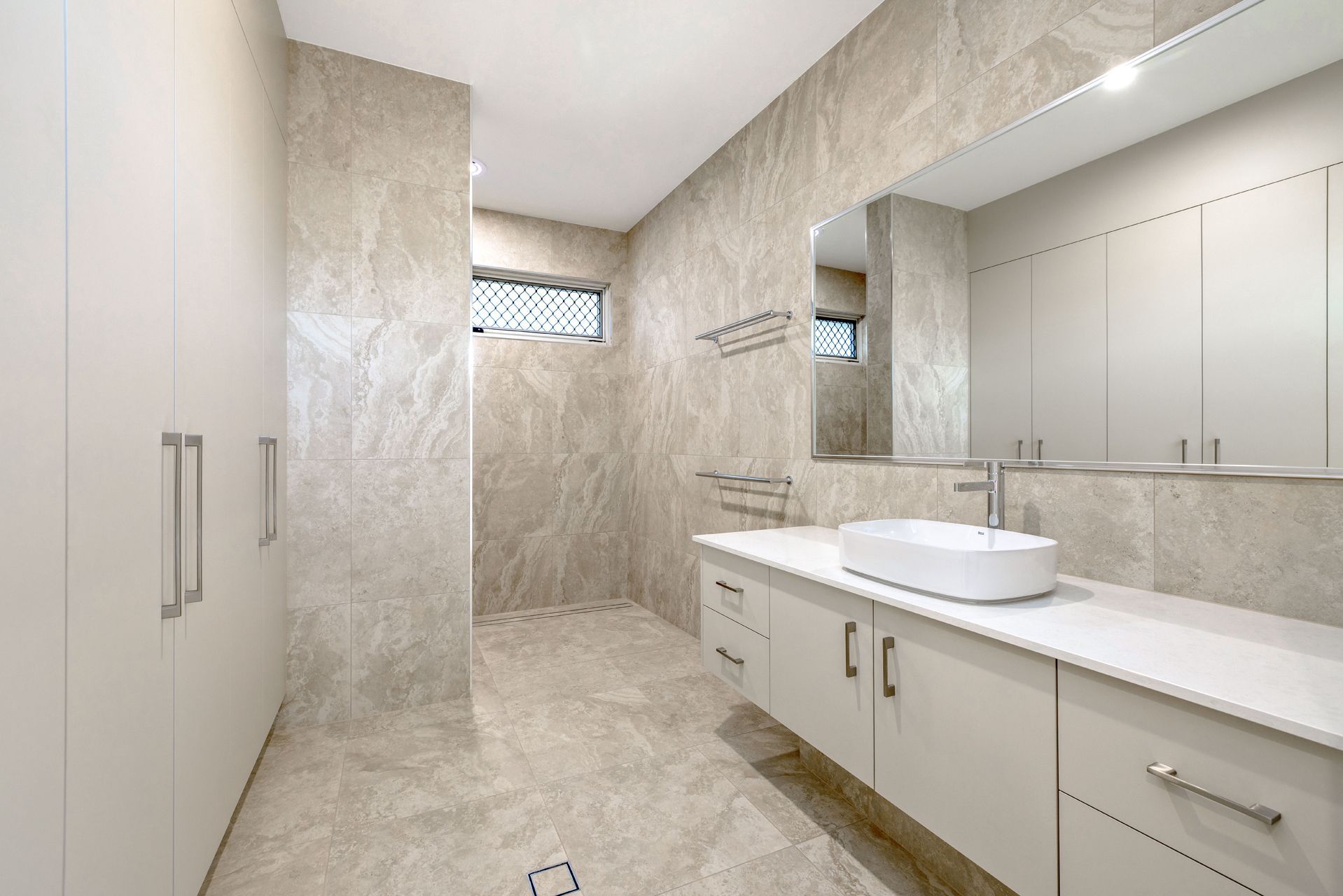 A Modern Bathroom With Light-toned Marble-patterned Walls — Ashlee Jones Homes in Gordonvale, QLD