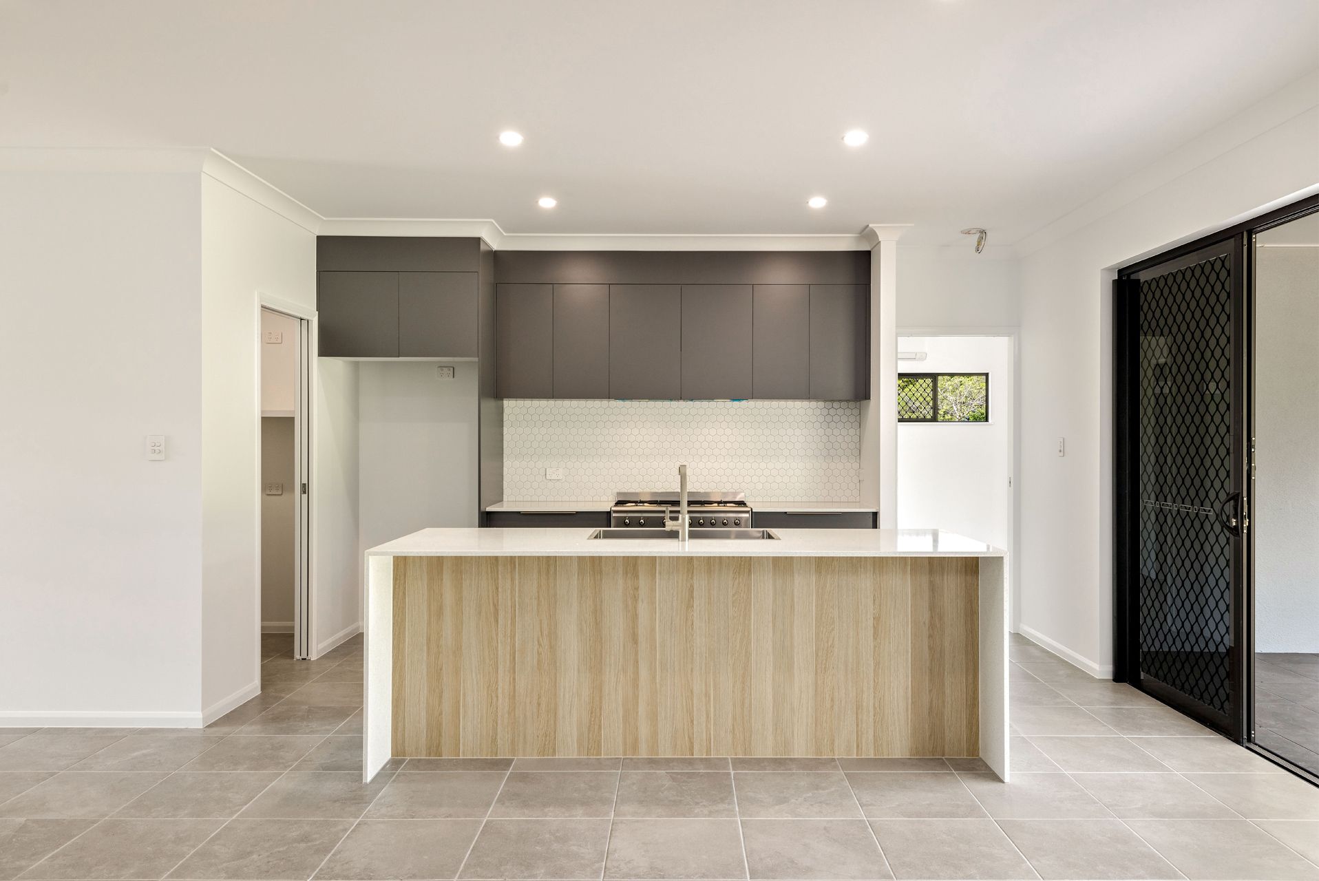 Modern Kitchen With a Light Wood Island, Dark Grey Cabinets — Ashlee Jones Homes in Gordonvale, QLD