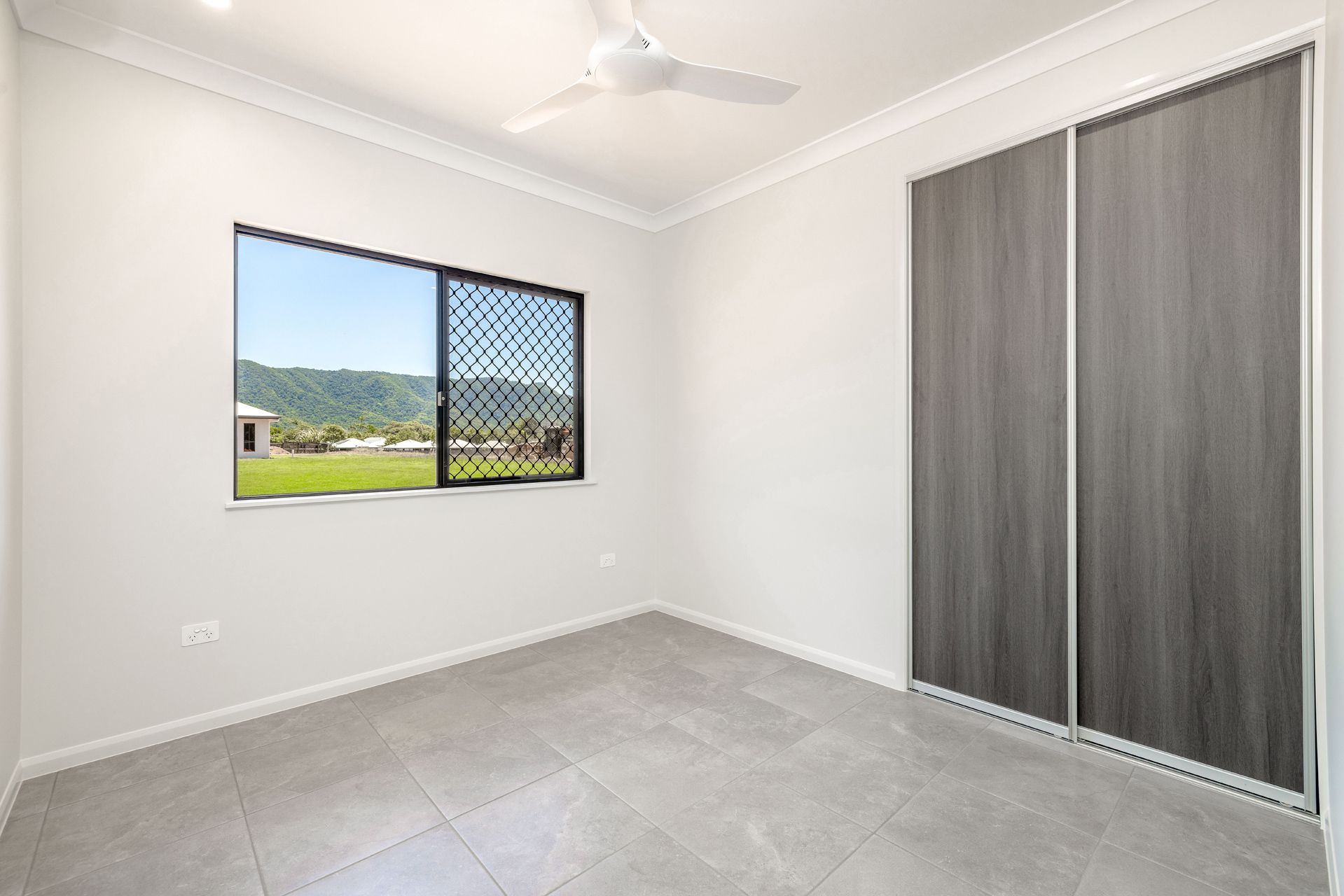 An Empty Bedroom With White Walls, Gray Tile Floors — Ashlee Jones Homes in Gordonvale, QLD