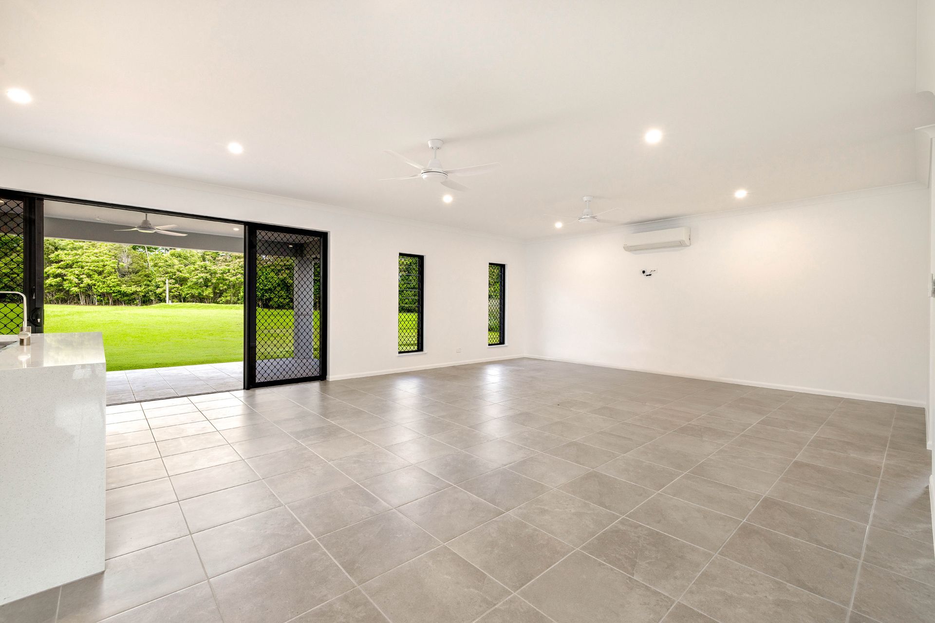 A Bright, Modern Room With Light Grey Tile Floors — Ashlee Jones Homes in Gordonvale, QLD