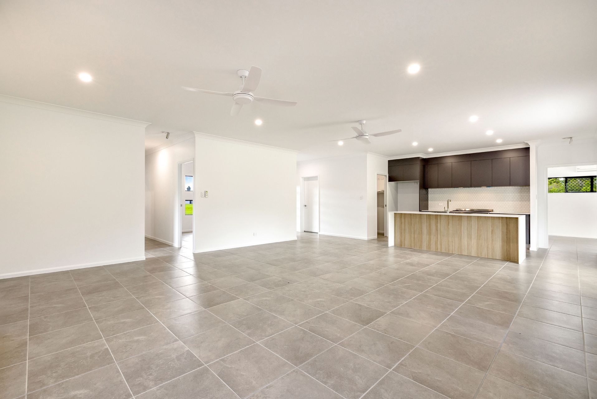 An Open-plan Living and Kitchen Area Featuring Large Grey Floor Tiles — Ashlee Jones Homes in Gordonvale, QLD