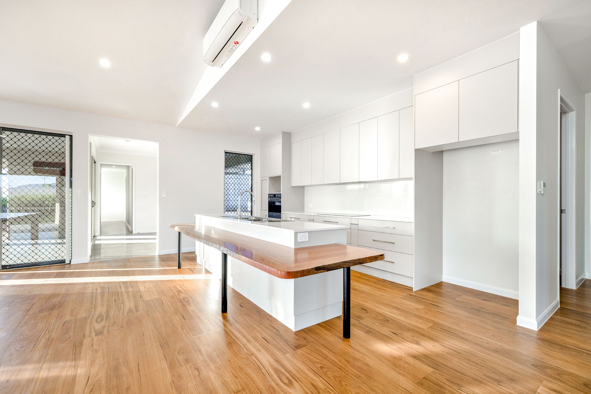 A Modern, Minimalist Kitchen With White Cabinets — Ashlee Jones Homes in Gordonvale, QLD