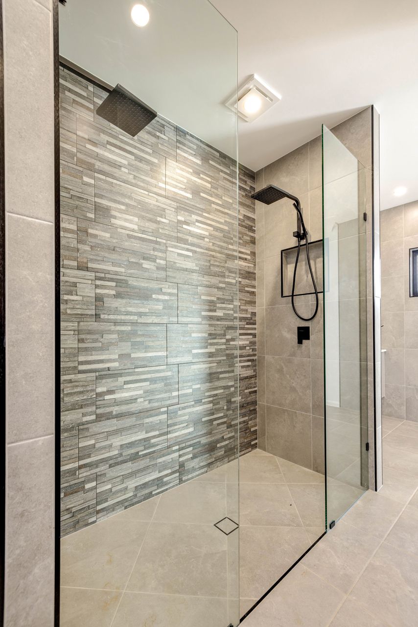 A Modern Walk-in Shower With a Textured Gray Stone Accent Wal — Ashlee Jones Homes in Gordonvale, QLD