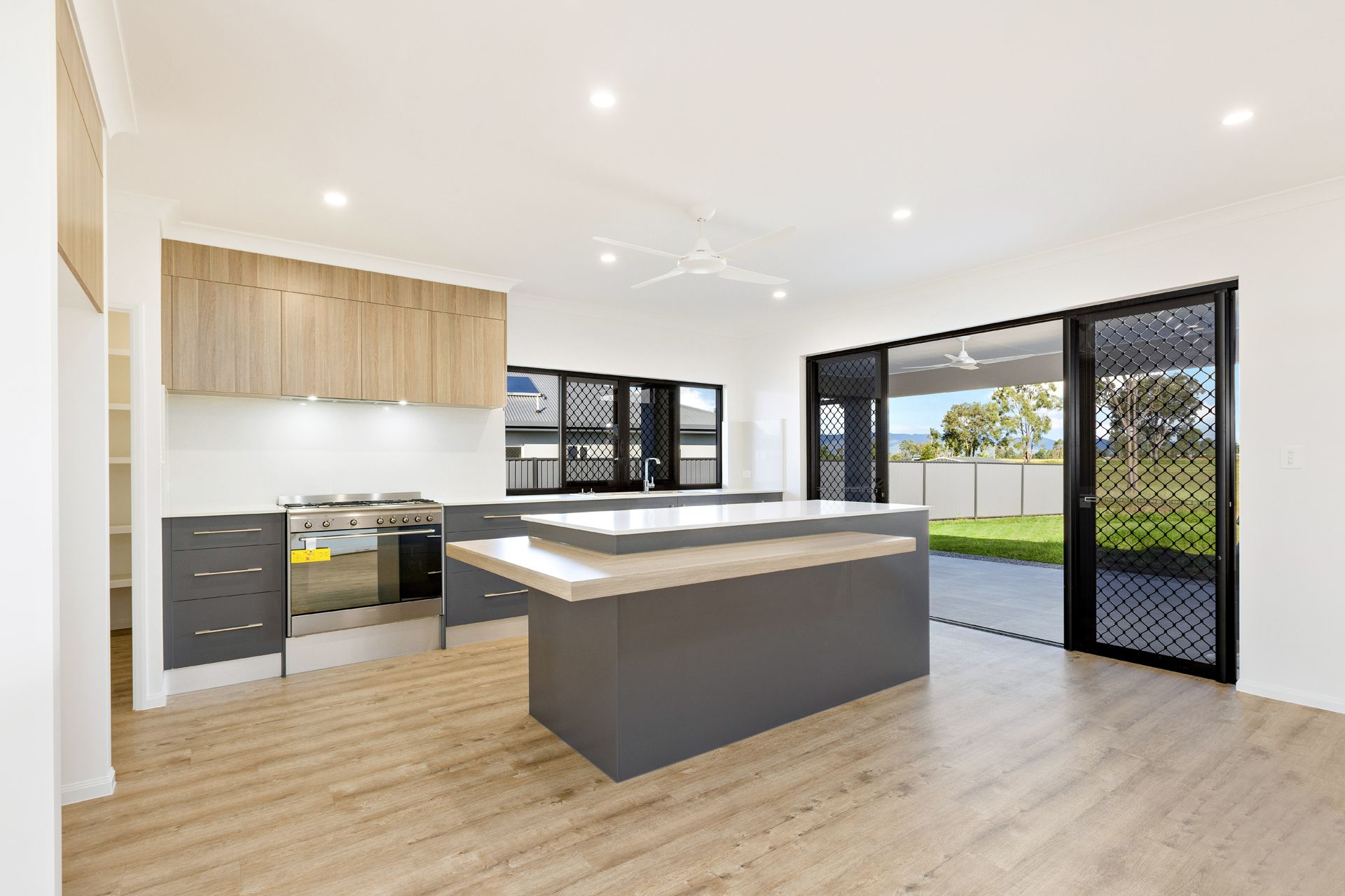 Modern Kitchen With Grey Lower Cabinets, Light Wood Upper Cabinets — Ashlee Jones Homes in Gordonvale, QLD