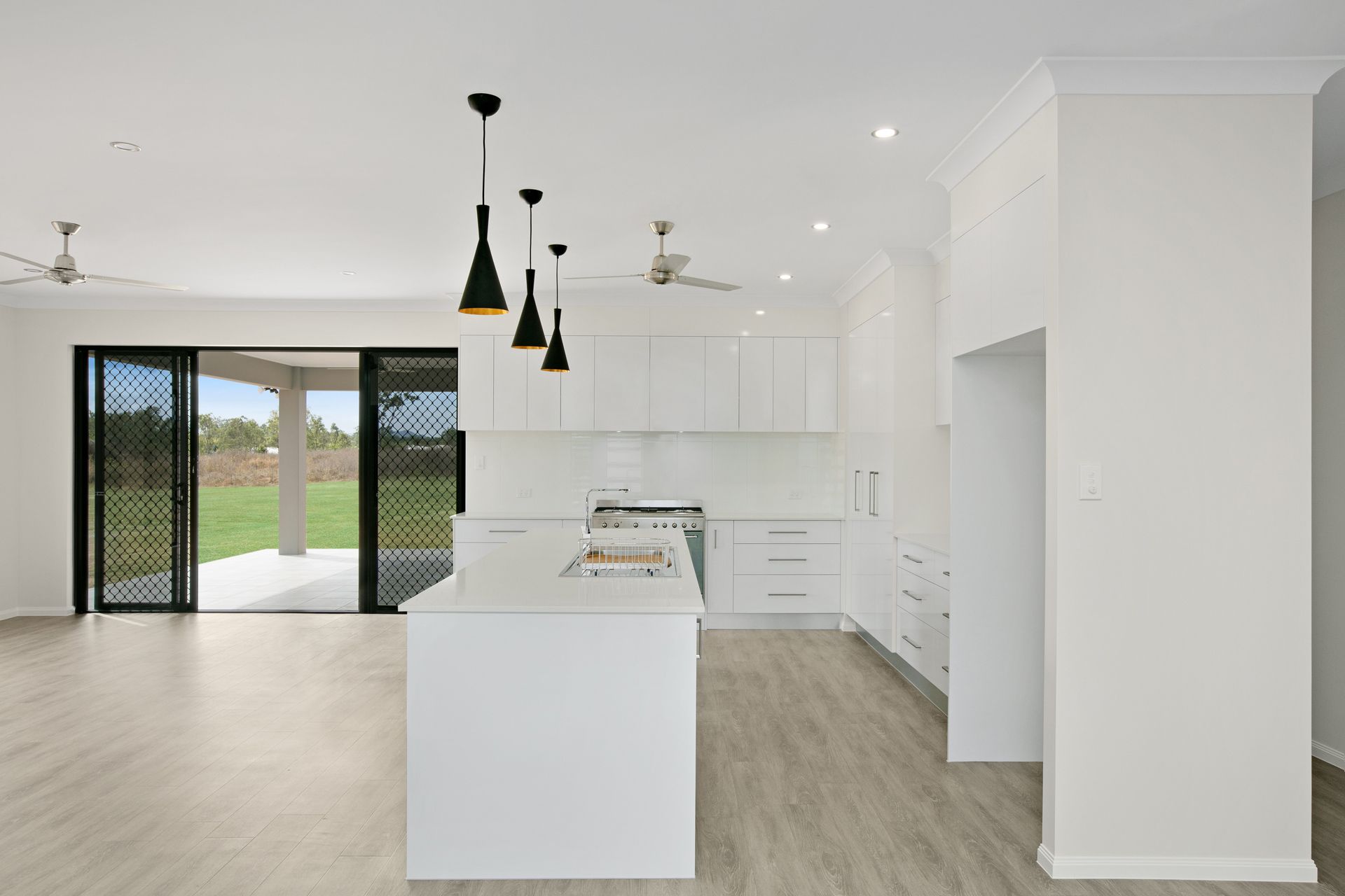 Modern, Bright Kitchen Featuring a White Island, Sleek Cabinetry — Ashlee Jones Homes in Gordonvale, QLD