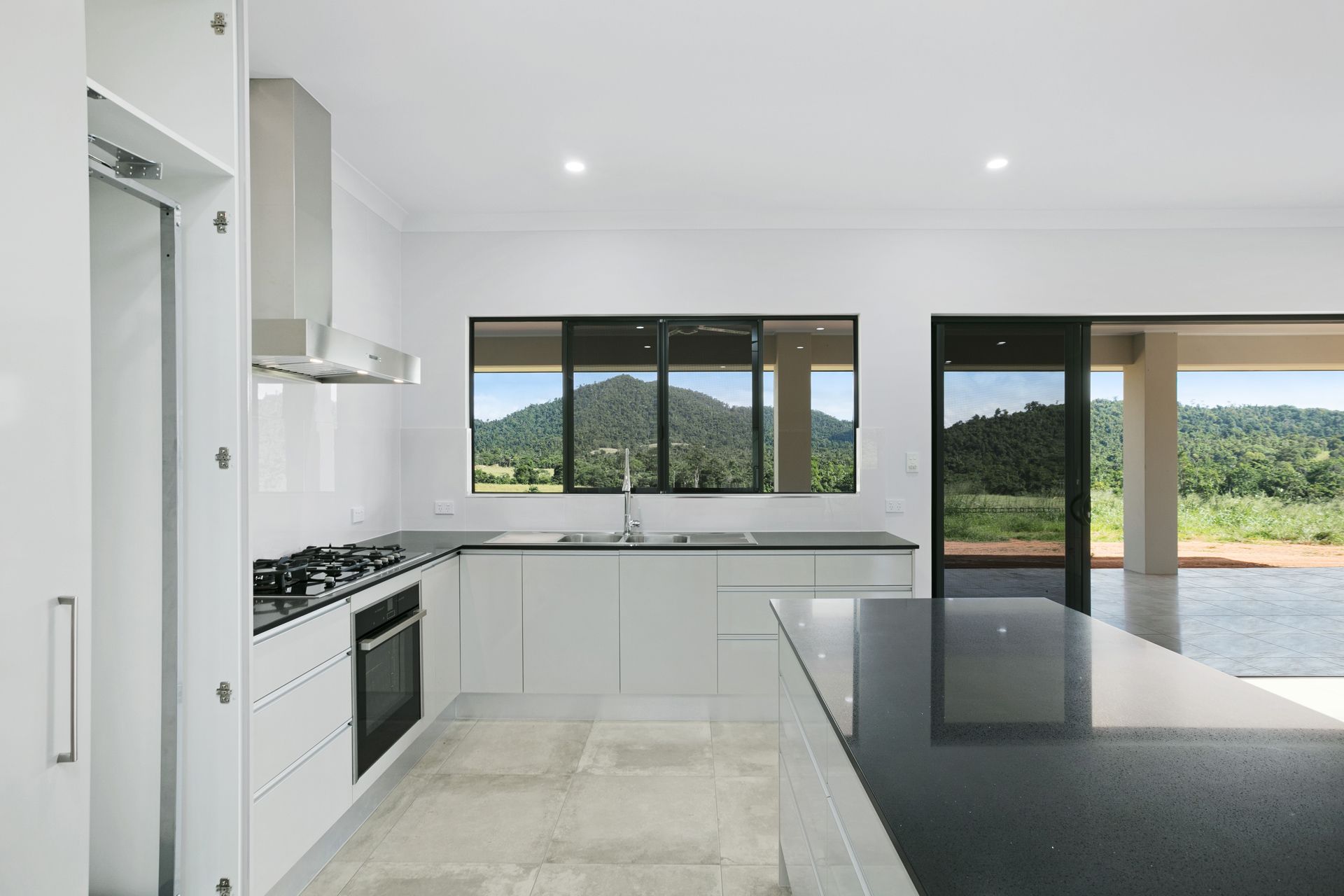 Modern White Kitchen With a Black Countertop Island — Ashlee Jones Homes in Gordonvale, QLD